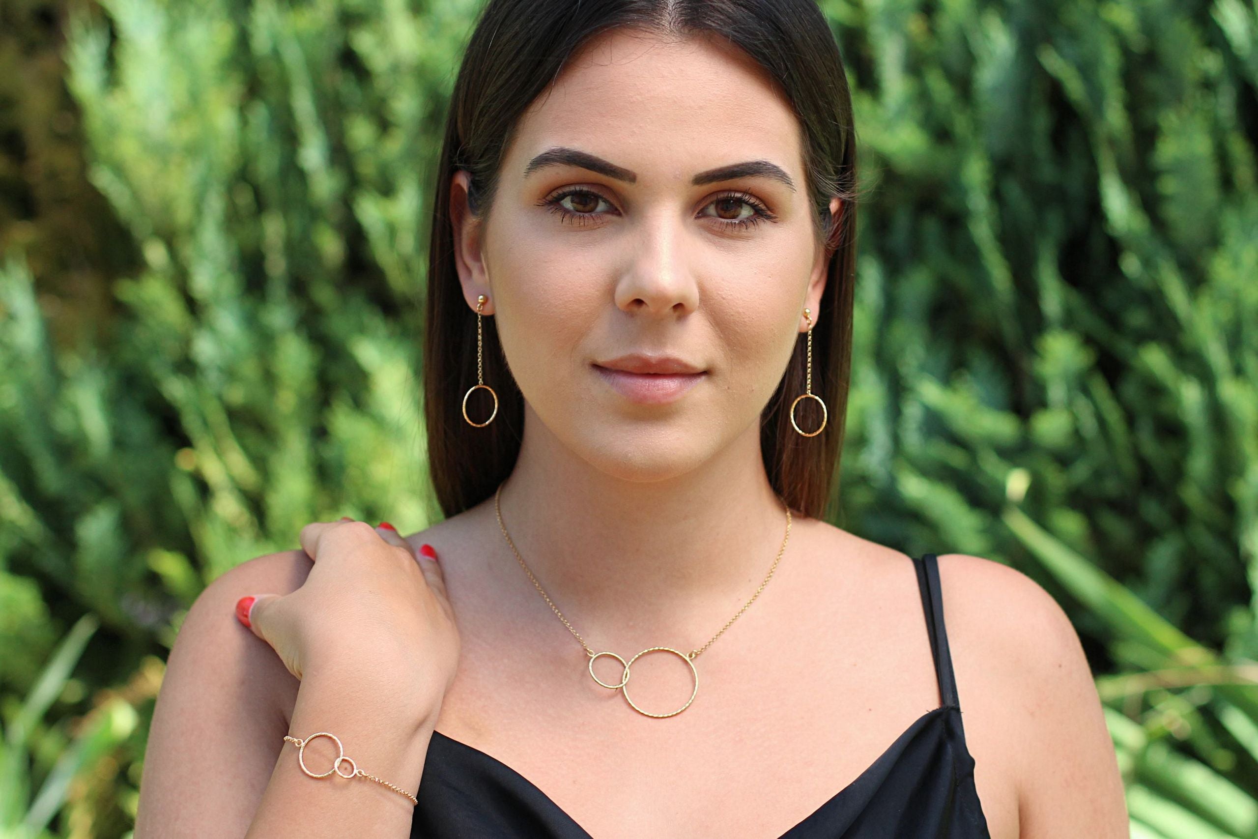 Eine diamantierte Ankerkette aus vergoldetem Silber mit zwei ineinander greifenden Kreisen, getragen von einer Dame.