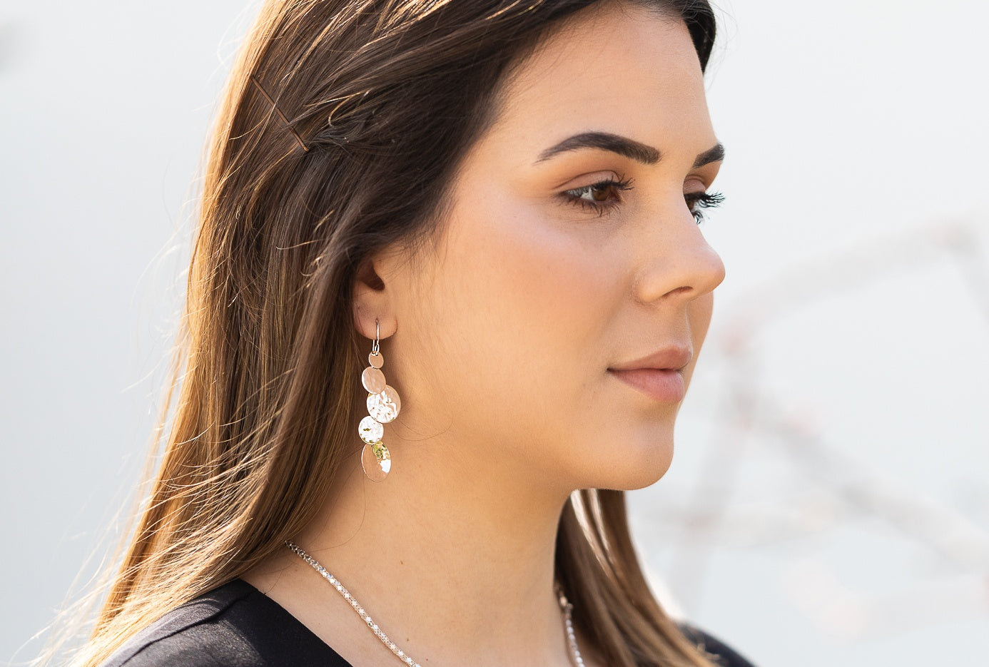 Gehämmerte Ohrhänger aus Silber, getragen am Ohr einer Dame. Die Ohrhänger bestehen aus fünf verschieden großen geschmiedeten Silberscheiben.