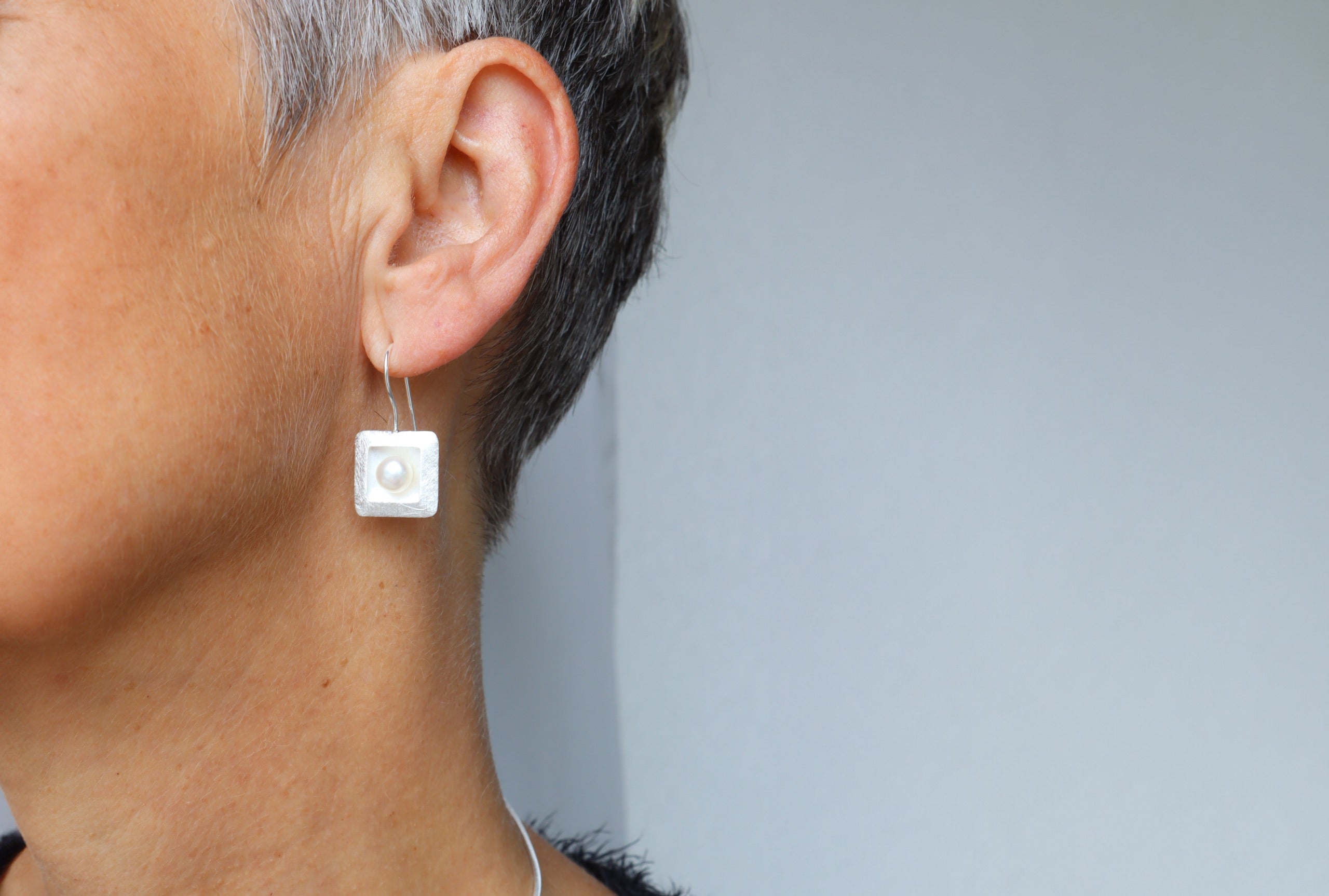 Ohrhänger aus Silber für Damen mit einem quadratischen Zierelement, in denen mittig jeweils eine Perle sitzt.