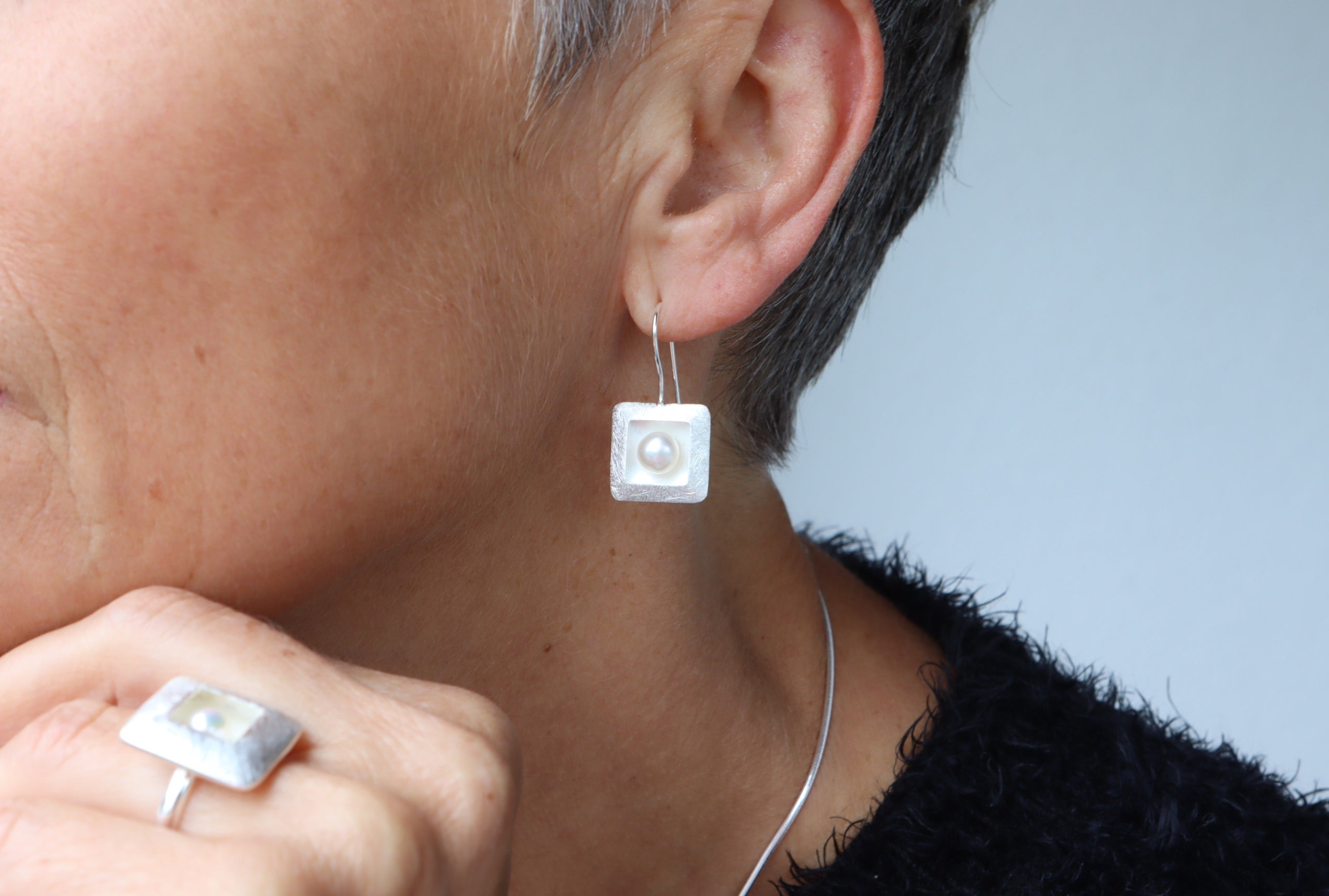 Ohrhänger aus Silber für Damen mit einem quadratischen Zierelement, in denen mittig jeweils eine Perle sitzt.