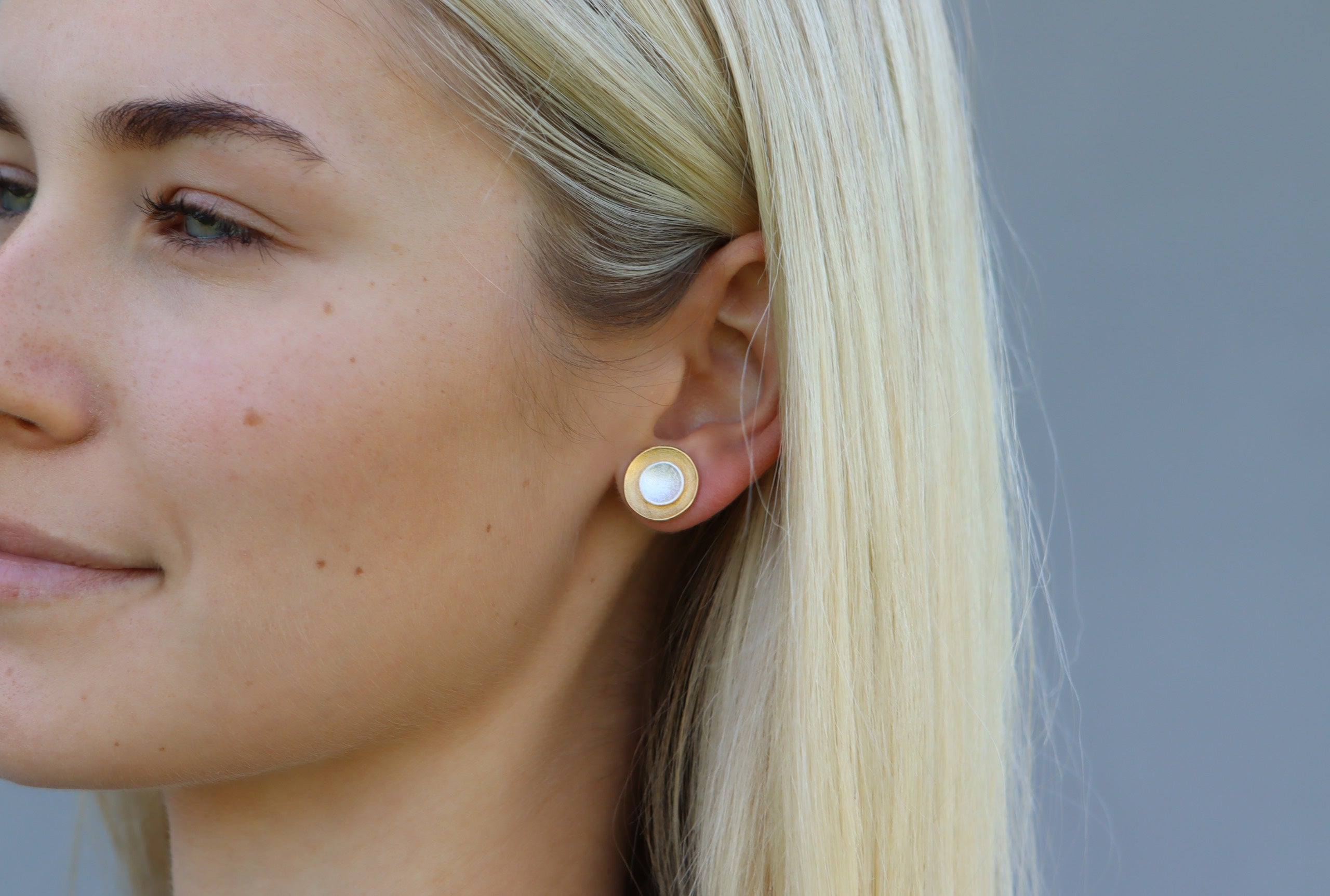 Frei kombinierbare Ohrstecker in Form zweier Kreise aus jeweils einer äußeren Schale und einem inneren Stecker aus Silber. Die äußere Schale ist mit Gold plattiert ist.