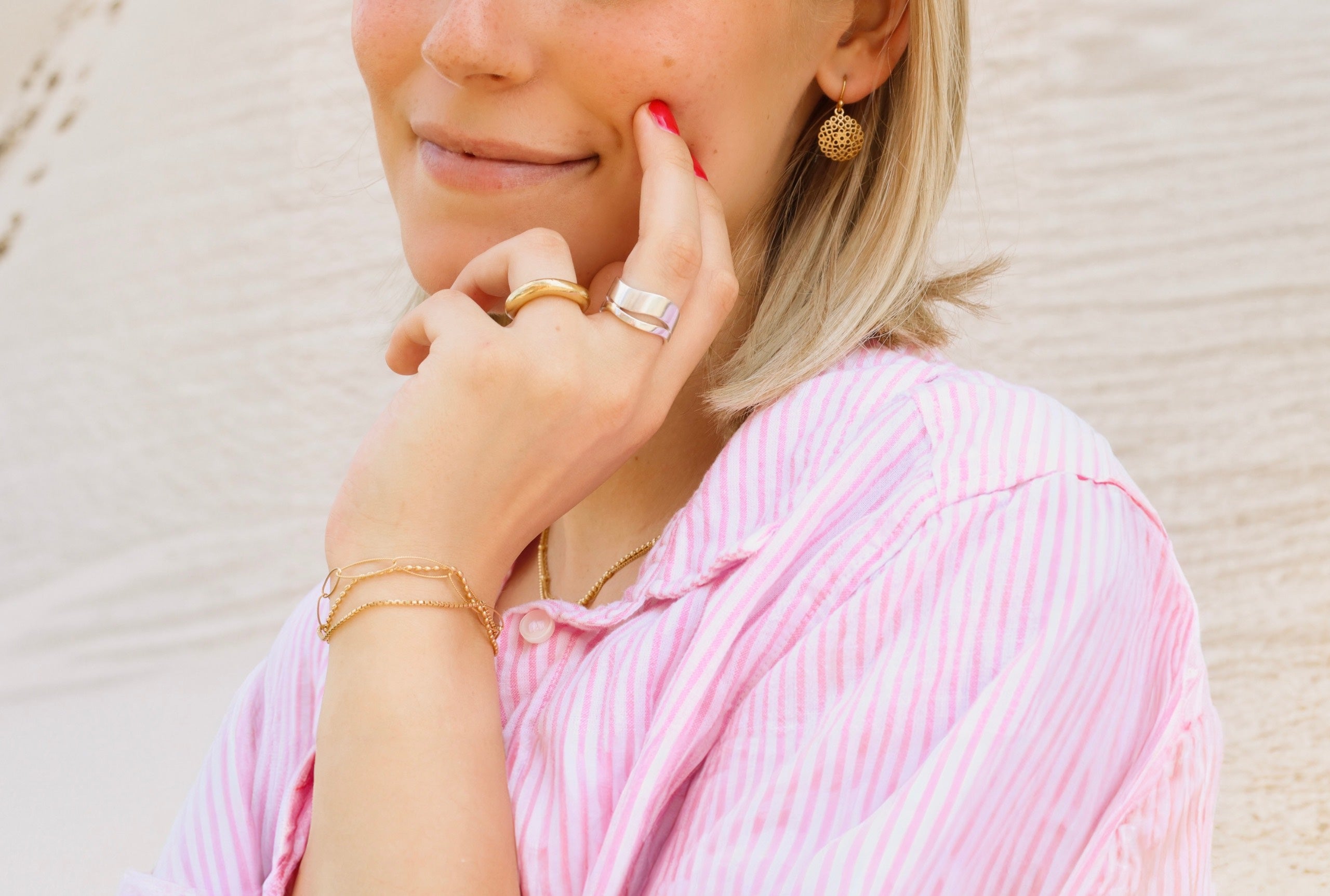 Ein Bandring aus Silber getragen an einer Damenhand, bestehend aus zwei kontastreich ineinander verschobenen Wellen mit fein mattierter Oberfläche.