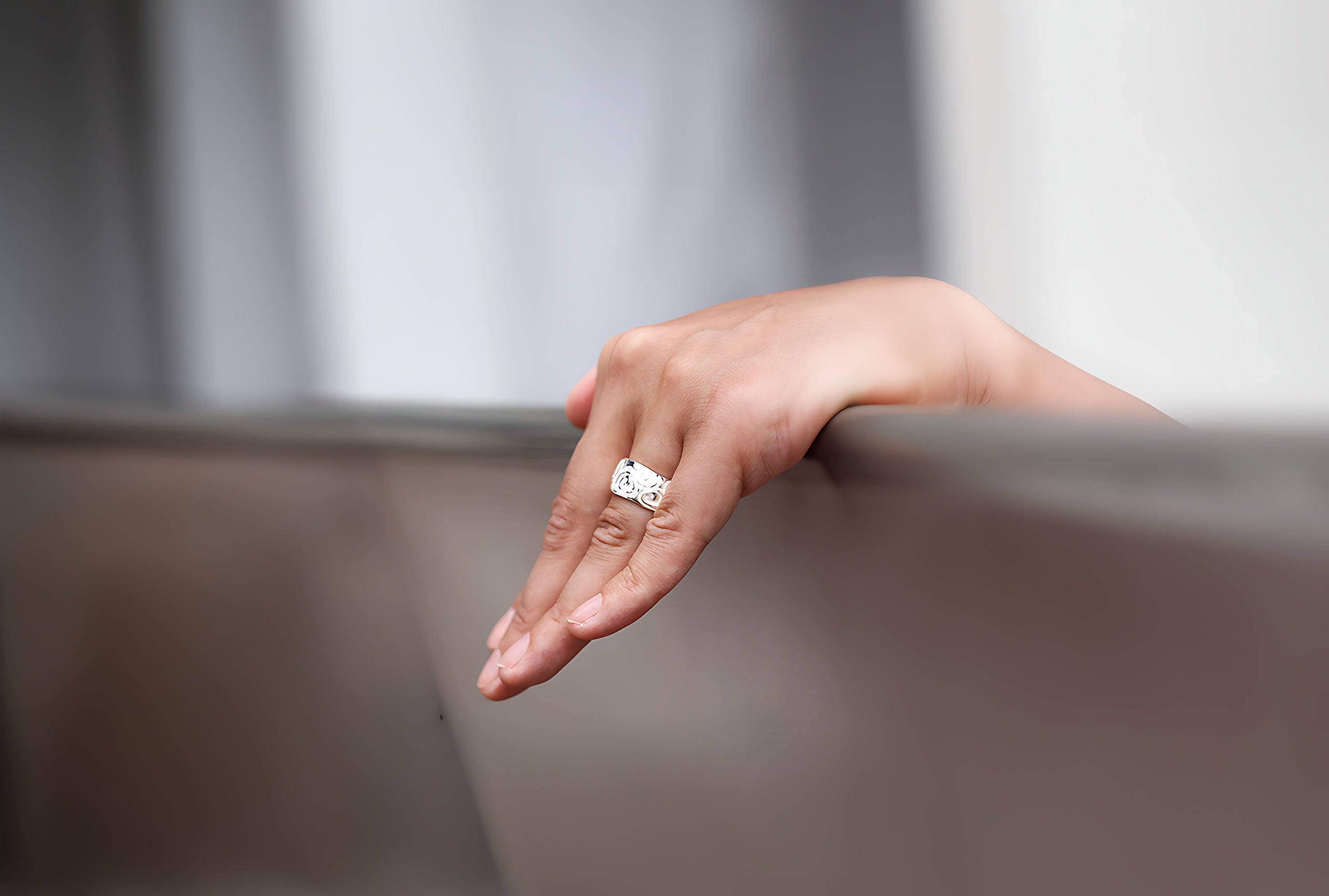 Bandring aus Silber für Damen mit einem durchlaufenden Ornamentband an der Oberfläche getragen an einer Damenhand.