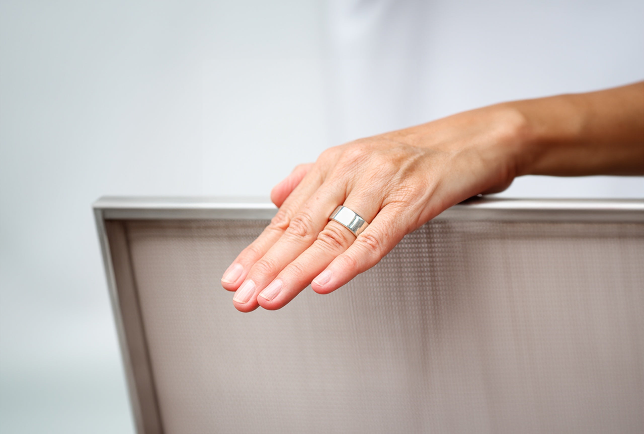 Ein massiver Bandring für Damen und Herren aus Silber mit einer glänzend polierten Oberfläche getragen an einer Damenhand.