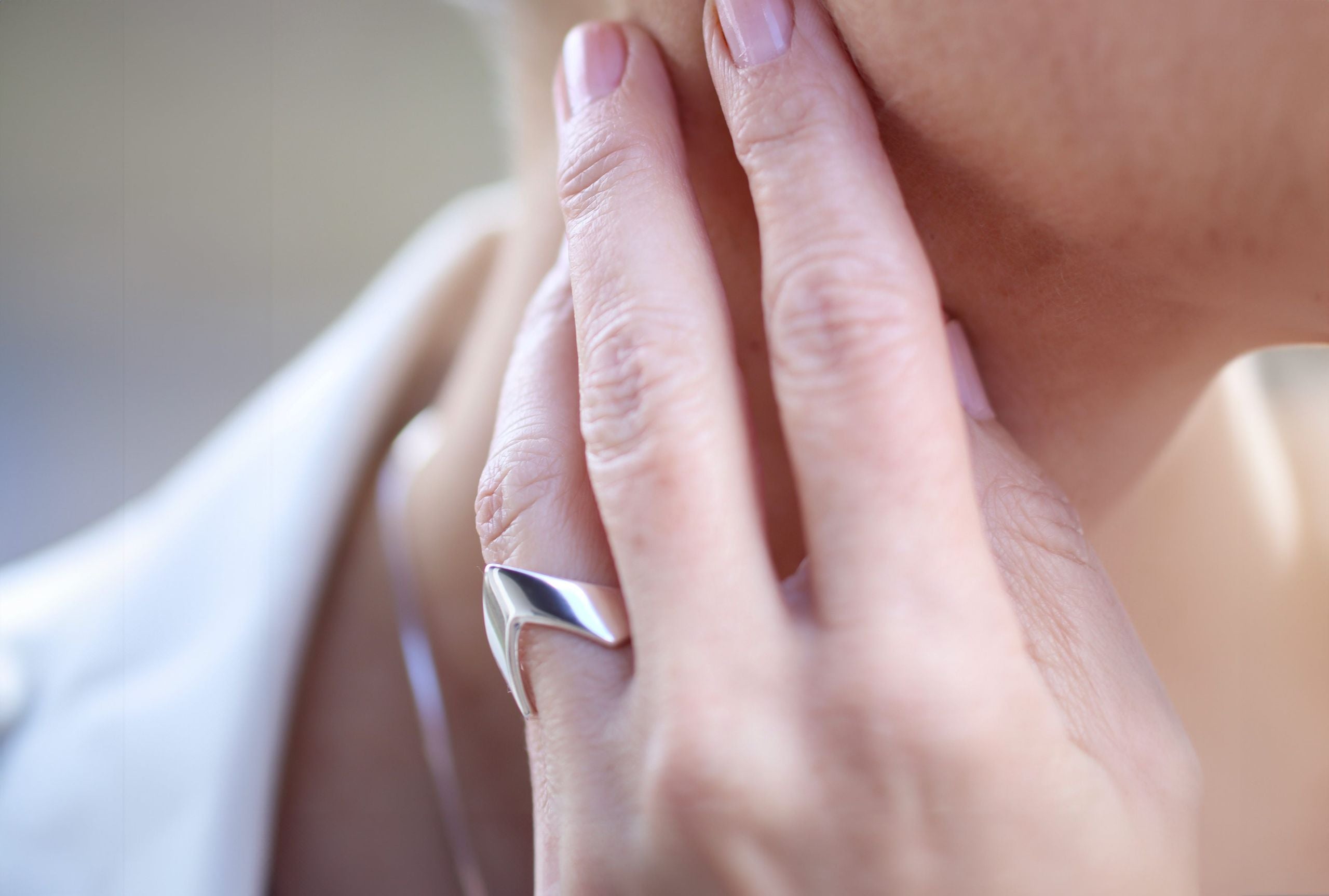 Ein spitz zulaufender Bandring aus Silber, der am Finger wie ein kleiner Pfeil nach vorne zeigt, getragen an einer Damenhand.