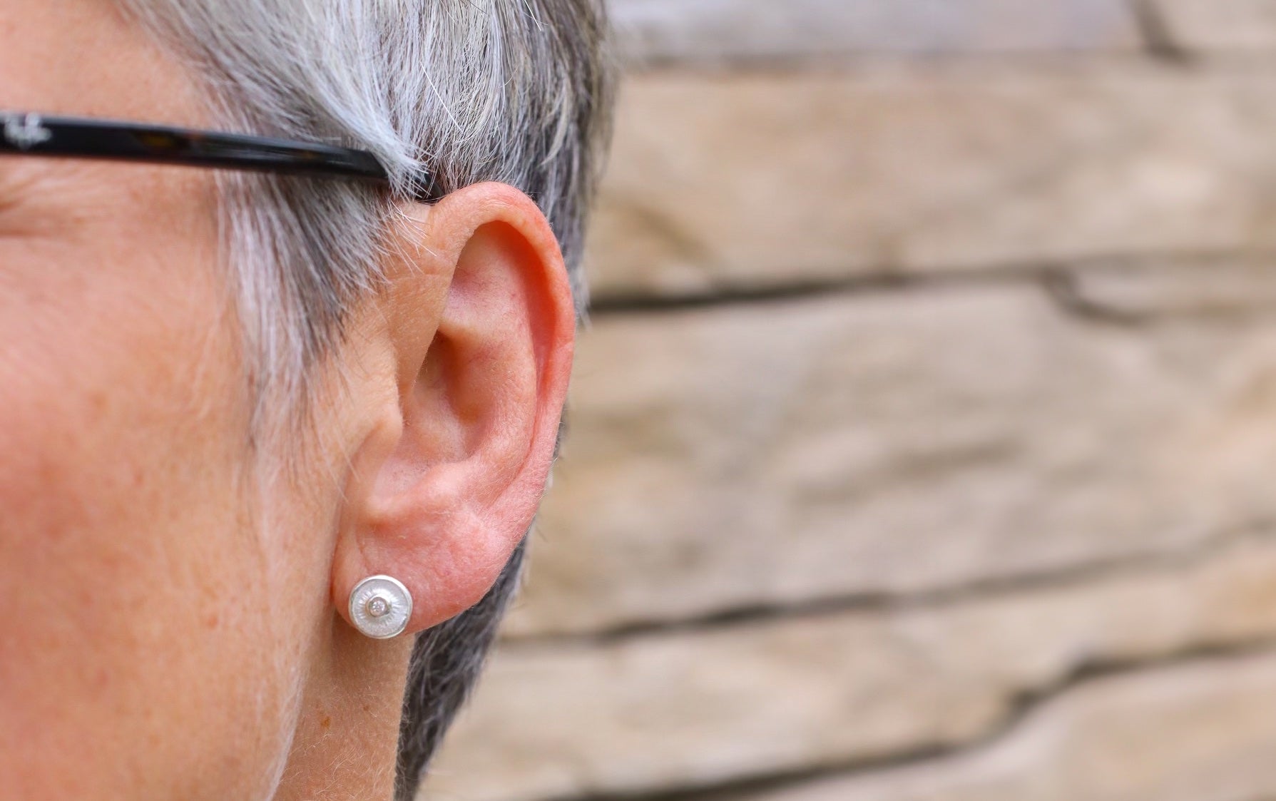 Fein modellierte runde Ohrstecker aus Silber für Damen mit einem mittig sitzenden kleinen Weißtopas.