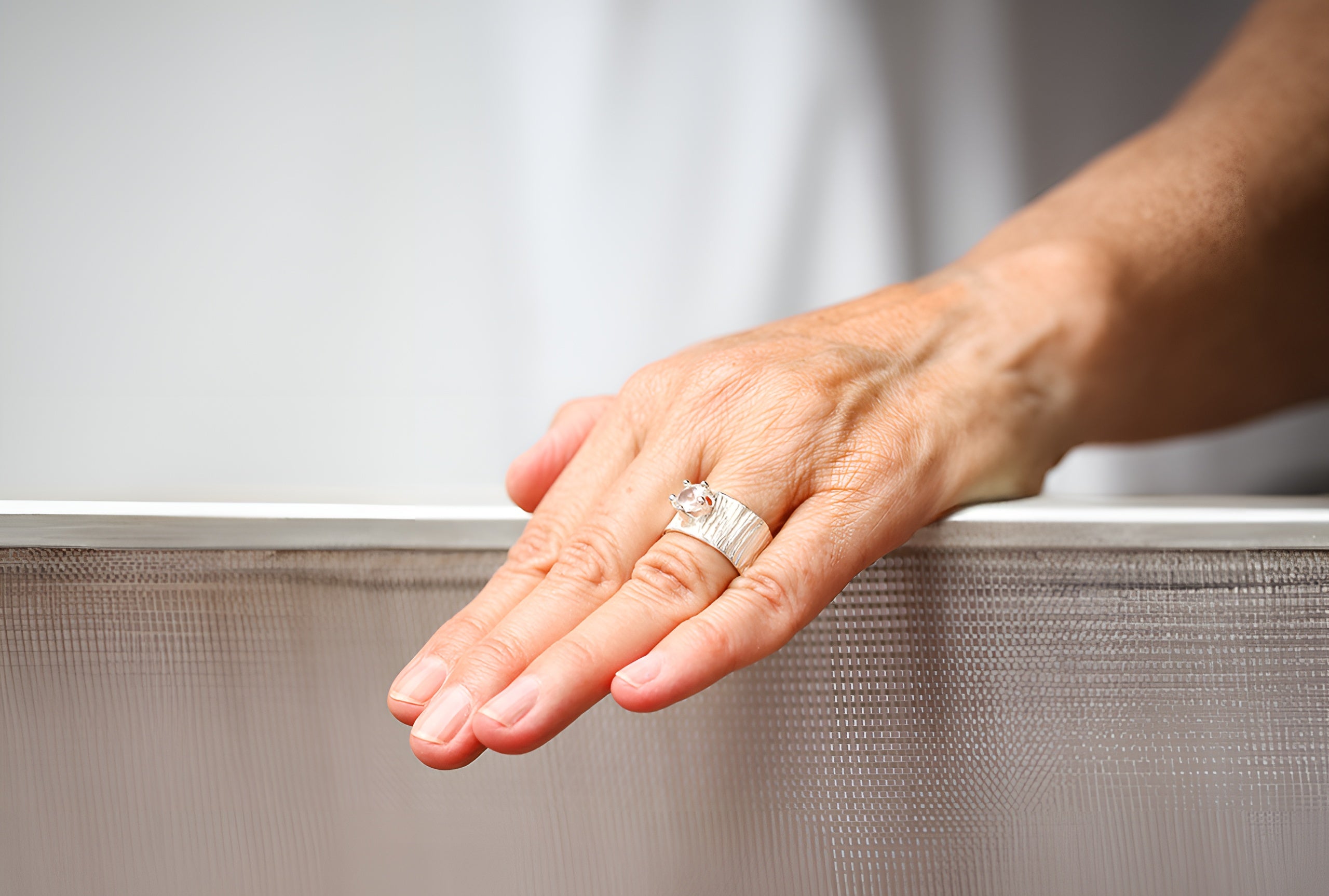 Ein Silberring mit Weißem Topas getragen an einer Damenhand. Der klare Topas im Sternschliff ist in einer Krone mit fünf Zacken gefasst.