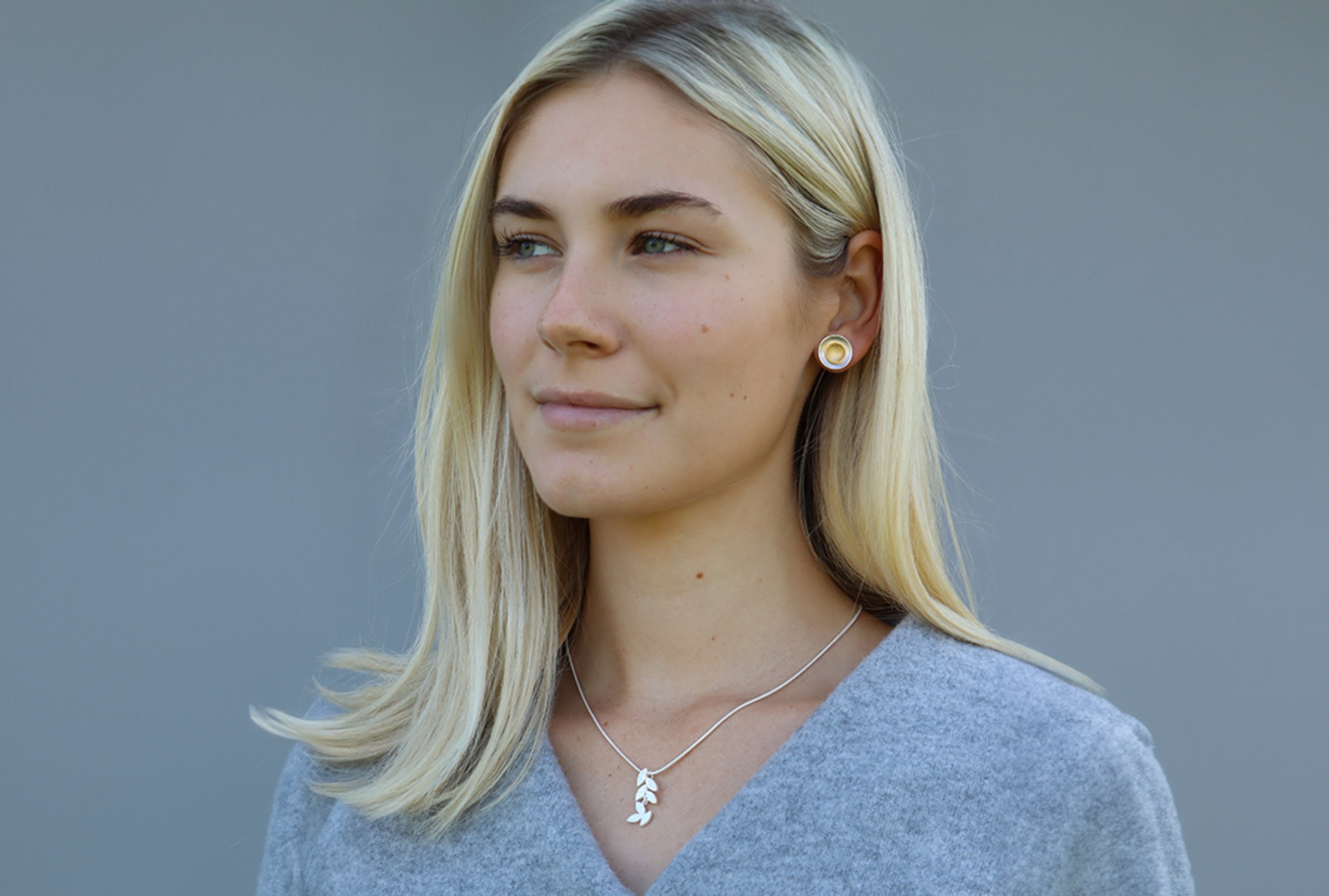 Ein kleiner Zweig als Damenanhänger aus Silber, getragen am Hals einer Dame.