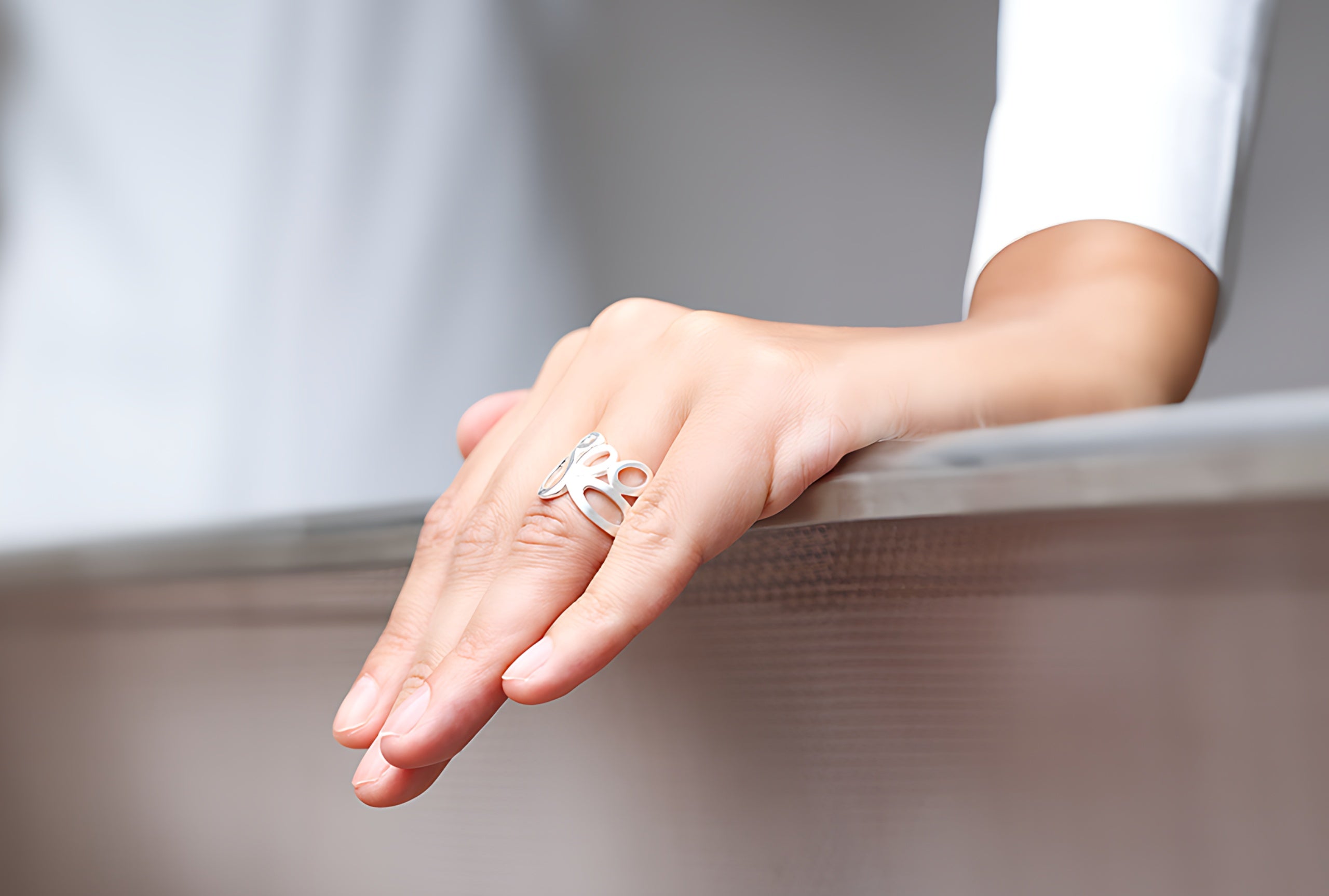Ein Motivring aus Silber im Design offen gearbeiteter Kreise, getragen an einer Damenhand.