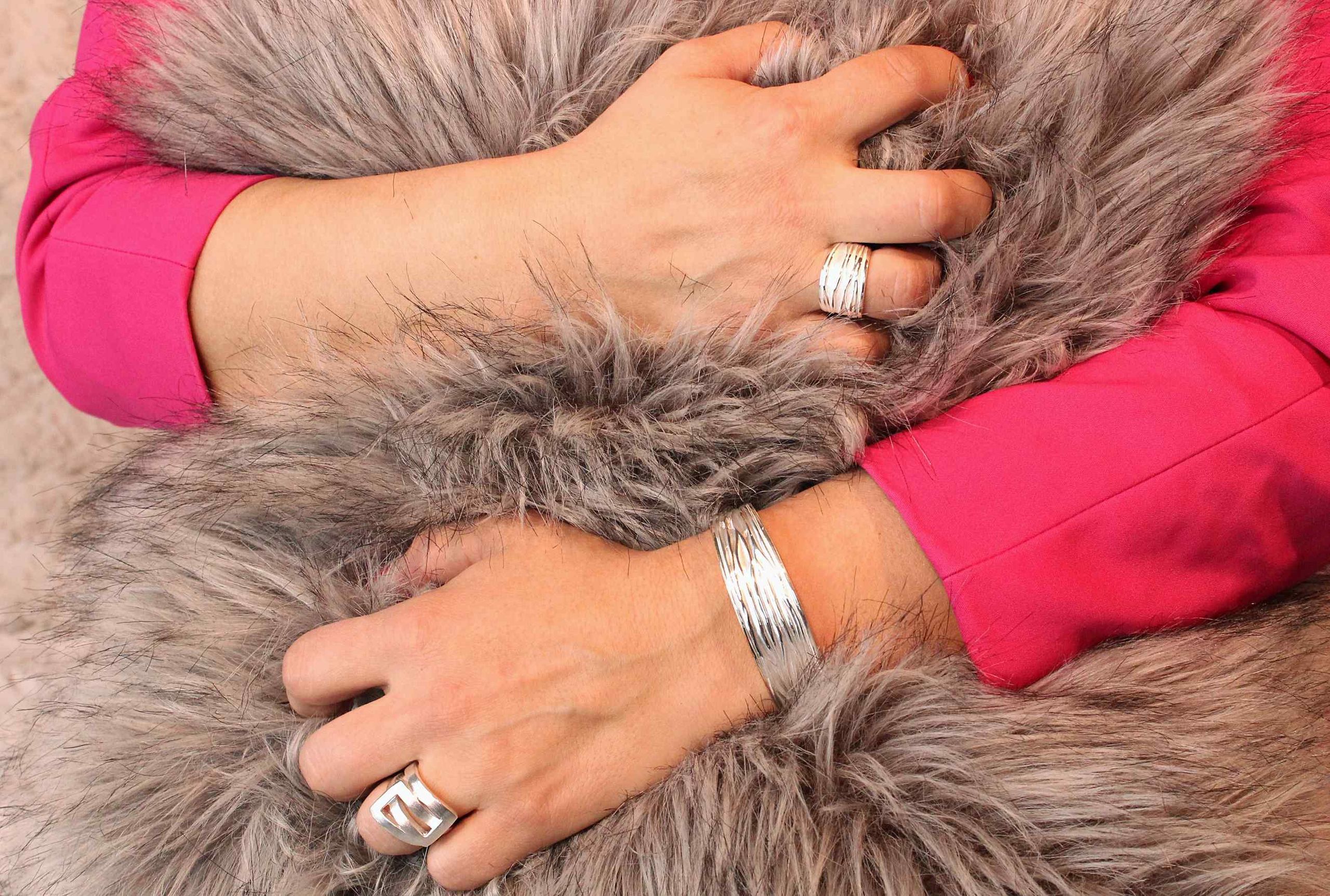 Ein Ring aus Silber für Damen, bestehend aus einer massiven Ringschiene und zwei ineinander greifenden Vierecken, getragen an einer Damenhand.