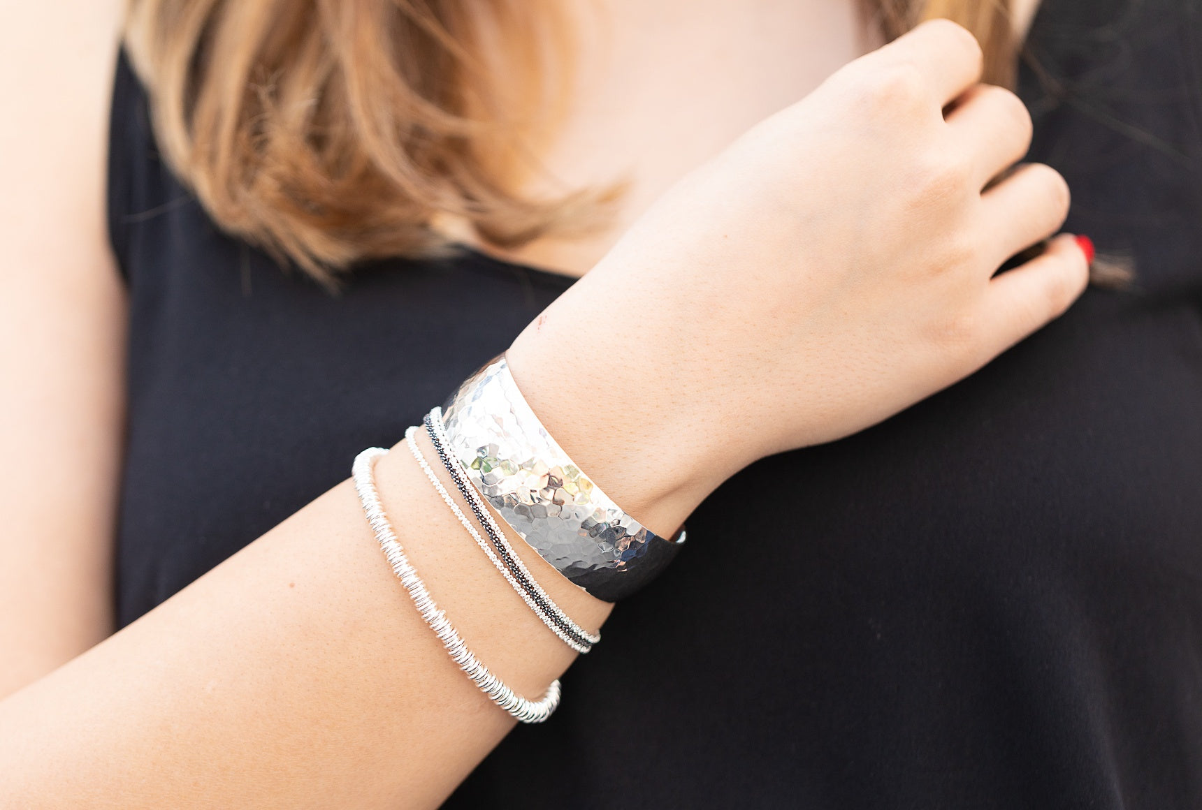 Ein Silberarmband aus vielen kleinen Silberringen mit einem dekorativen Verschluss, getragen am Handgelenk einer Dame.
