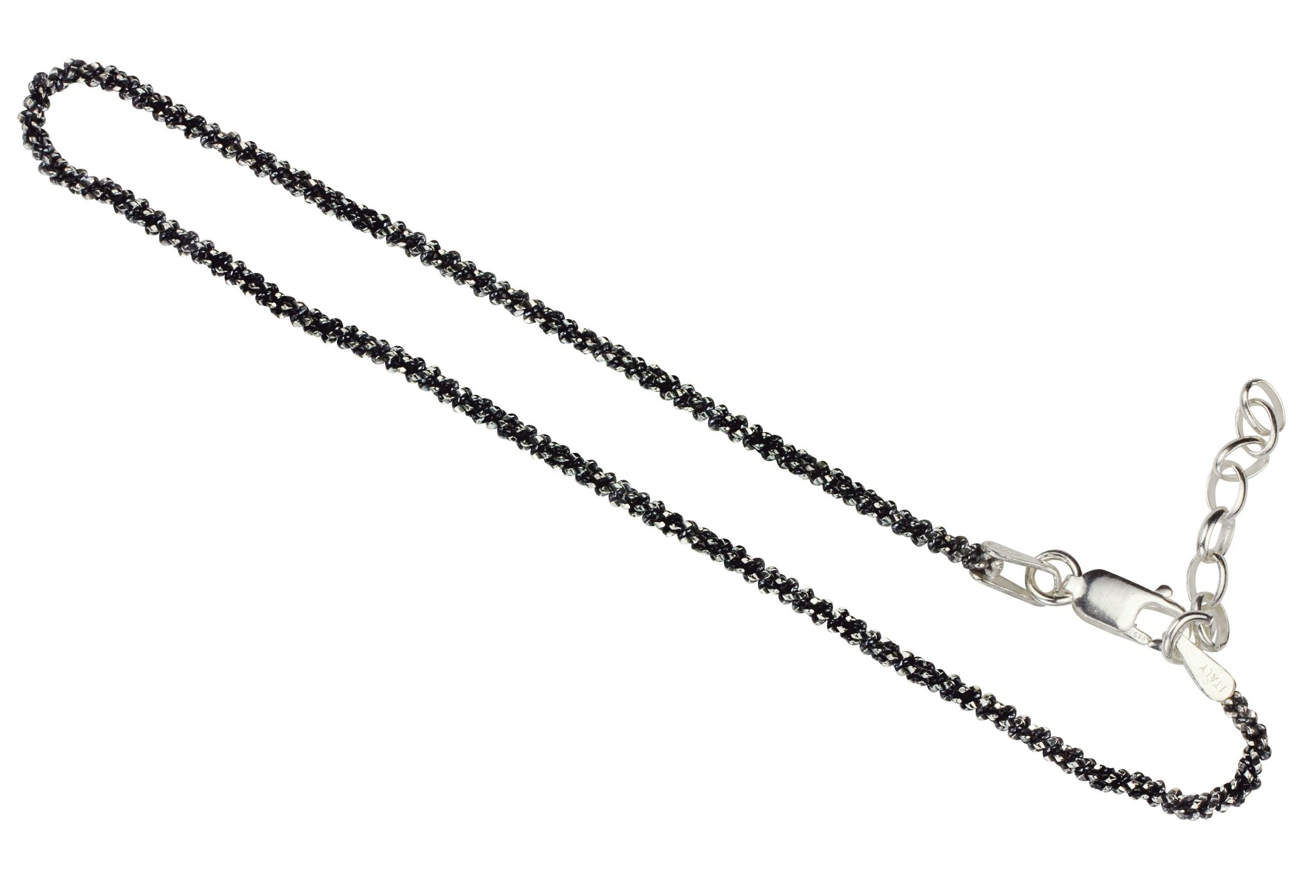 Geschwärztes Criss-Cross-Armband aus Silber für Damen mit einem geschmeidigen Geflecht und einer angeschliffenen funkelnden Oberfläche.