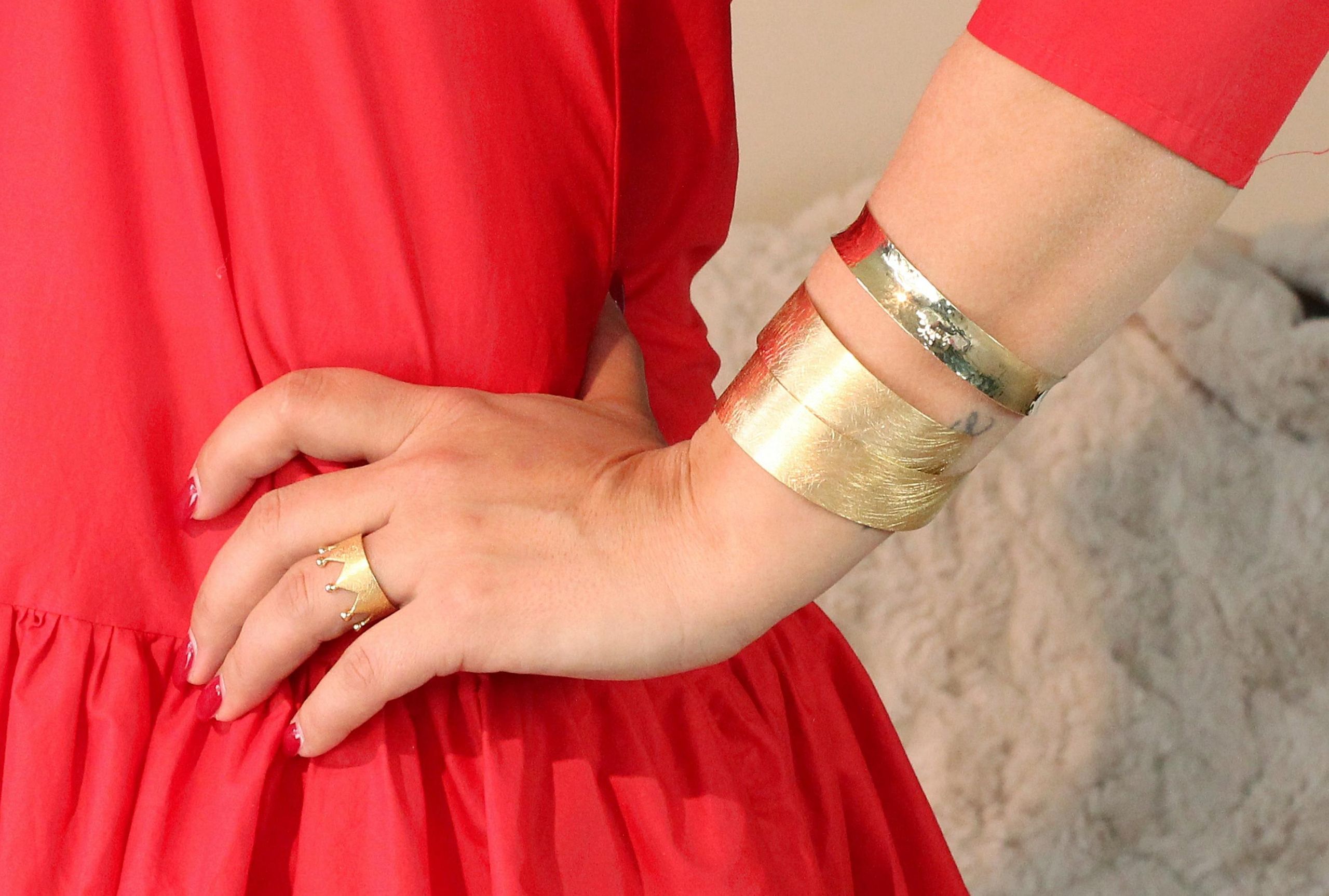 Ein Kronenring mit acht Zacken und acht Kügelchen an der Spitze, gefertigt aus Silber und mit Gold plattiert, getragen an einer Damenhand.