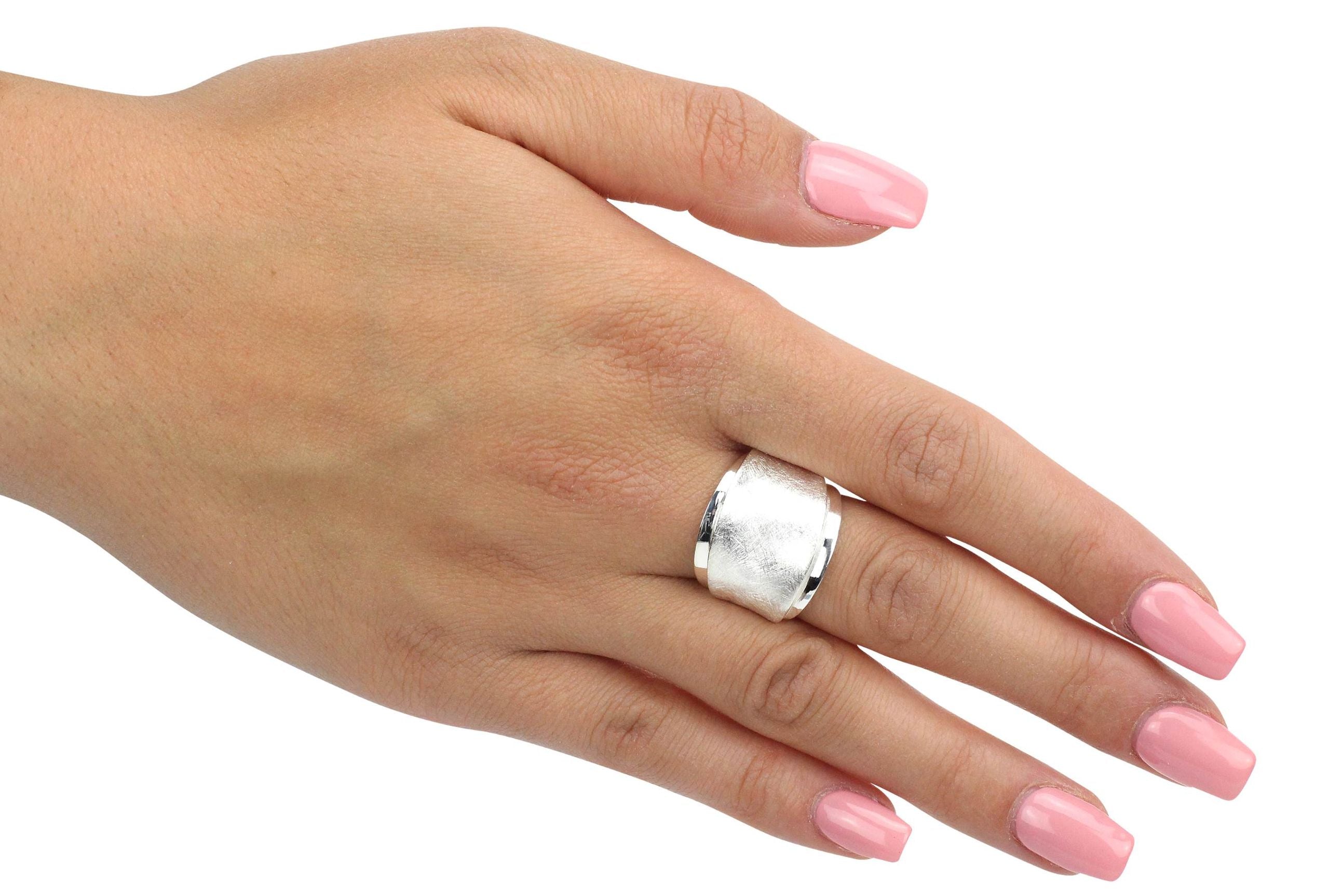 Ein Design Bandring aus Silber, bei dem ein mattierter und ein glänzender Ring gestuft übereinander liegen, getragen an einer Damenhand.