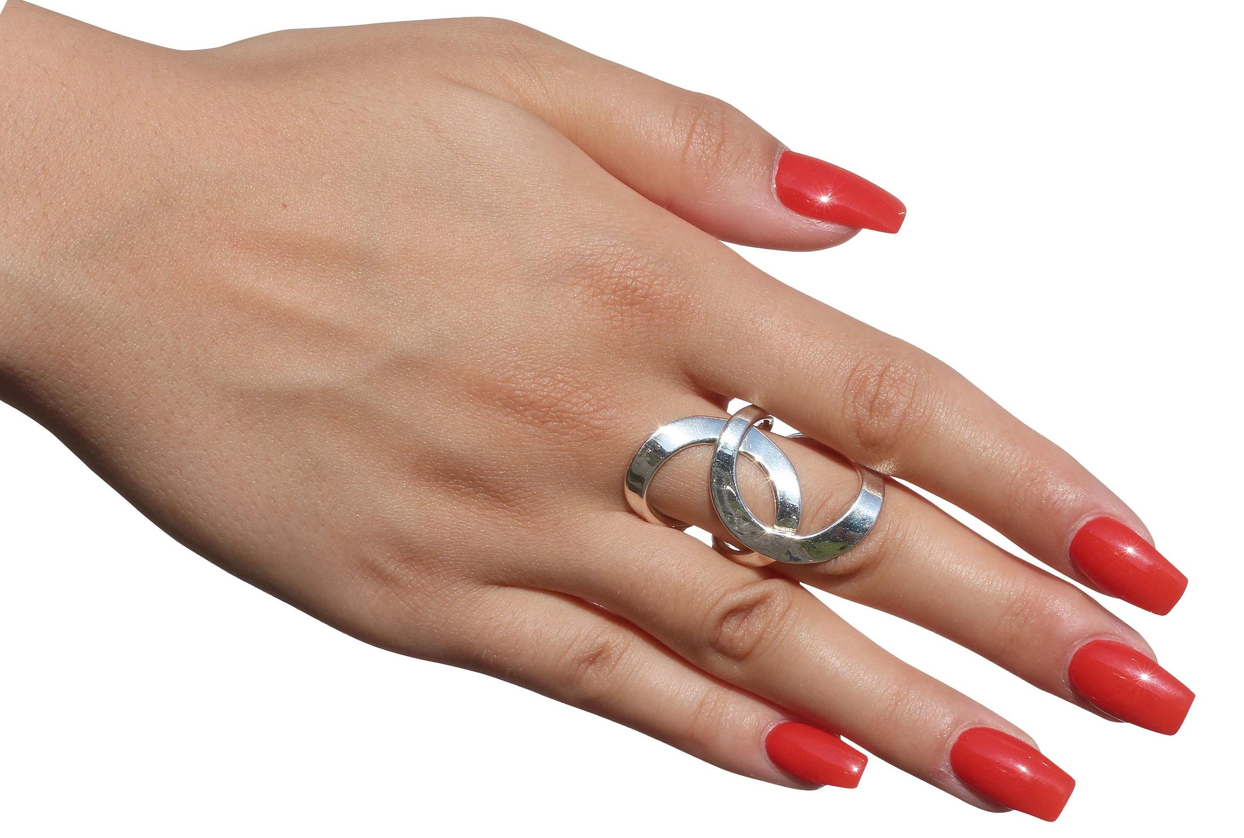 Geschmiedeter Damenring aus zwei Kreisen, die kunstvoll ineinander verschlungen sind, getragen an einer Damenhand. Der Ring ist geschmiedet und hat eine glänzende Oberfläche.