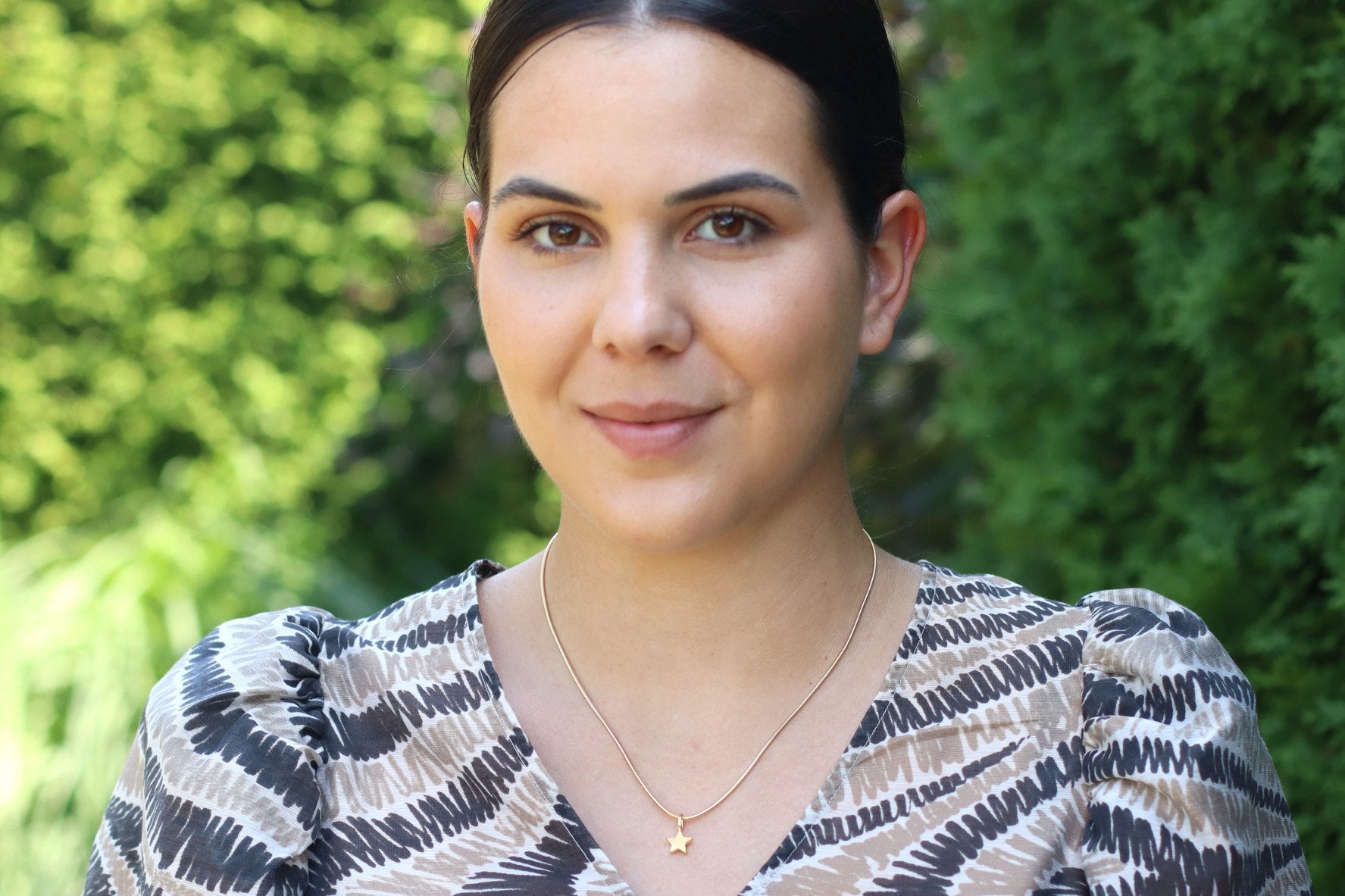 Massiv gearbeiteter Sternchen Anhänger aus Silber mit vergoldeter Oberfläche, bei dem die Kette durch eine seitlich gebohrte Öse gefädelt wird, getragen mit einer goldplattierten Schlangenkette.