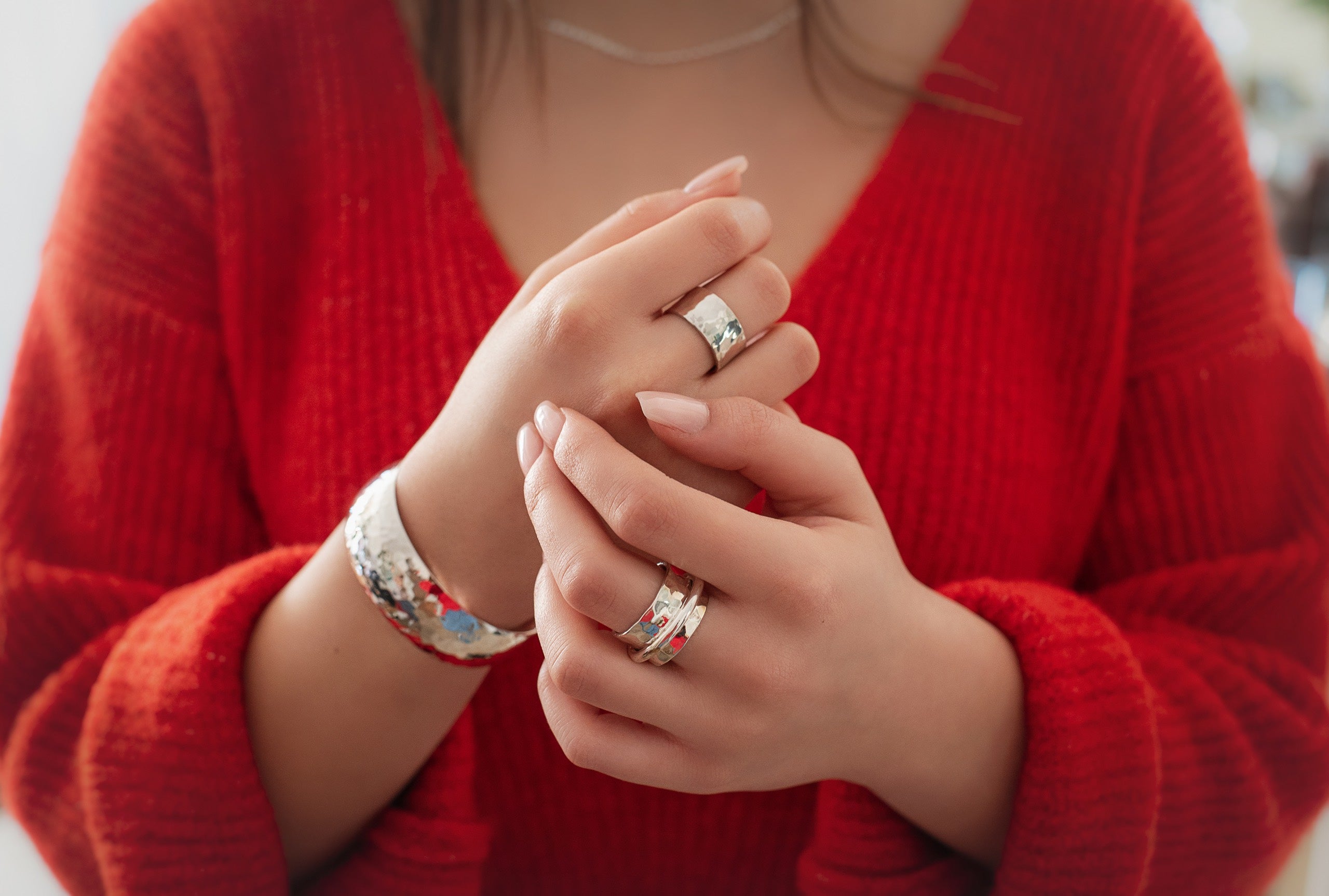 Ein moderner Schmiedering aus Silber getragen an einer Damenhand. Der Ring besteht aus einem massivem Bandring und einem kleinen Drehring, der unverlierbar darauf geschmiedet ist.