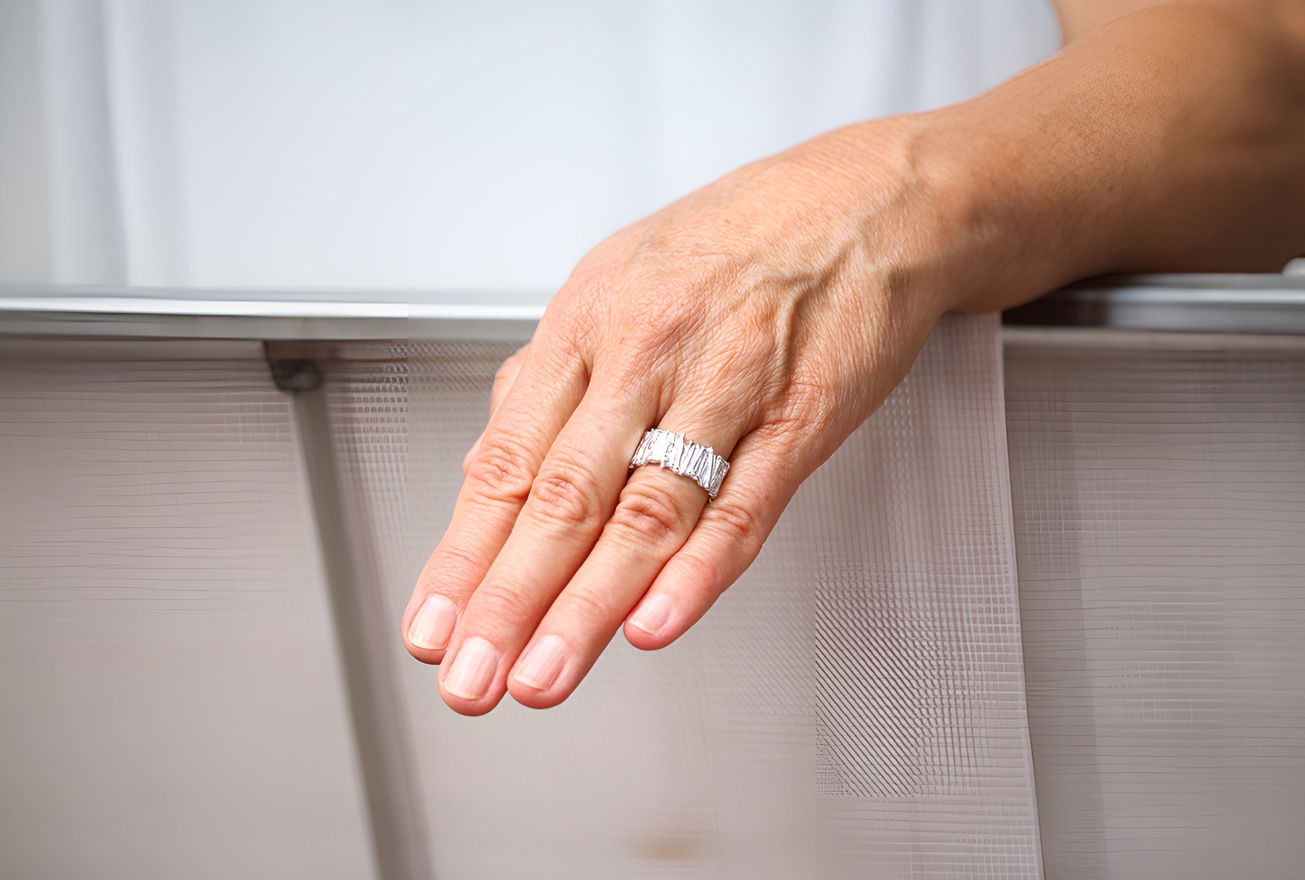 Ein Ring im Stäbchendesign für Damen und Herren aus Silber mit einer filigran gearbeiteten Oberfläche getragen an einer Damenhand.