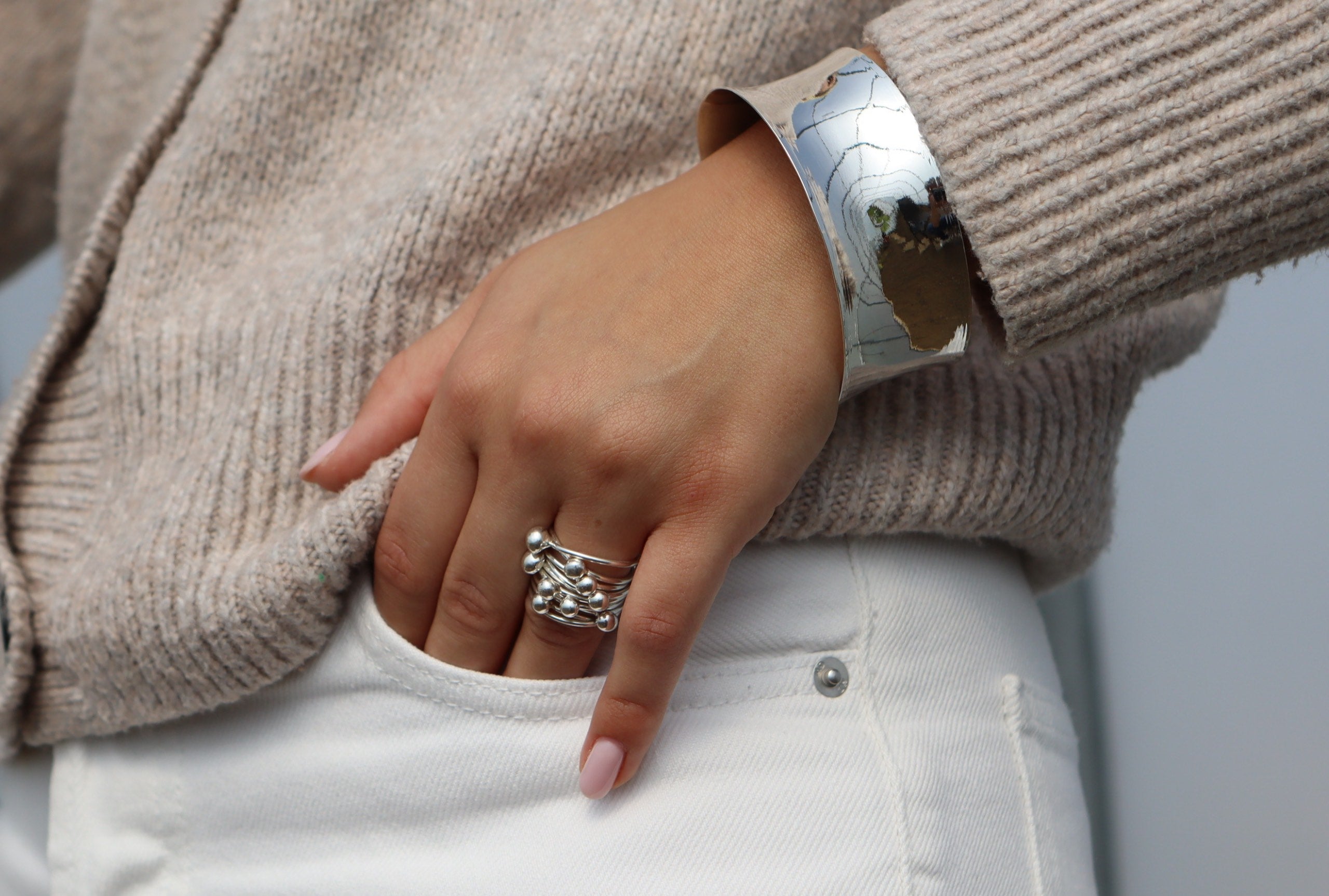 Kugelring aus Silber für Damen bestehend aus zehn beweglichen kleinen Ringen auf denen jeweils eine kleine Kugel thront, getragen an einer Damenhand.