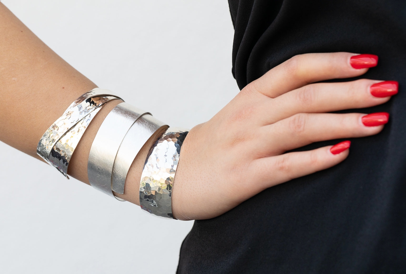 Gehämmerter Armreif aus Silber für Damen mit zwei diagonal sich überkreuzenden Silbersträngen, die kunstvoll verlötet sind, getragen am Handgelenk einer Dame.