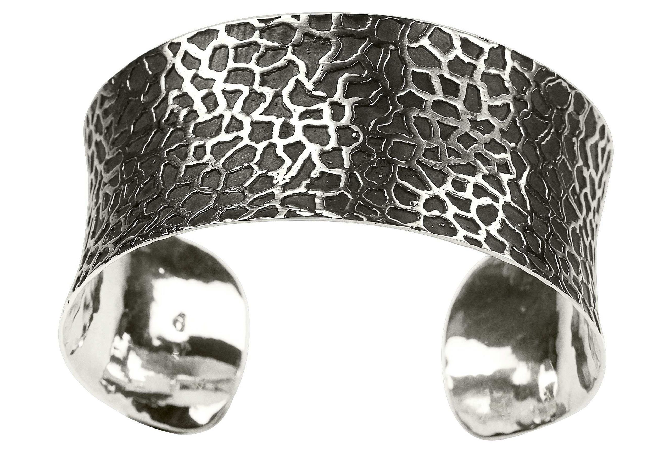 Breiter Armreif aus Silber für Damen mit einer Oberfläche, die durch teilweise Schwärzung des Silber eine Rochenleder-Optik entstehen lässt.