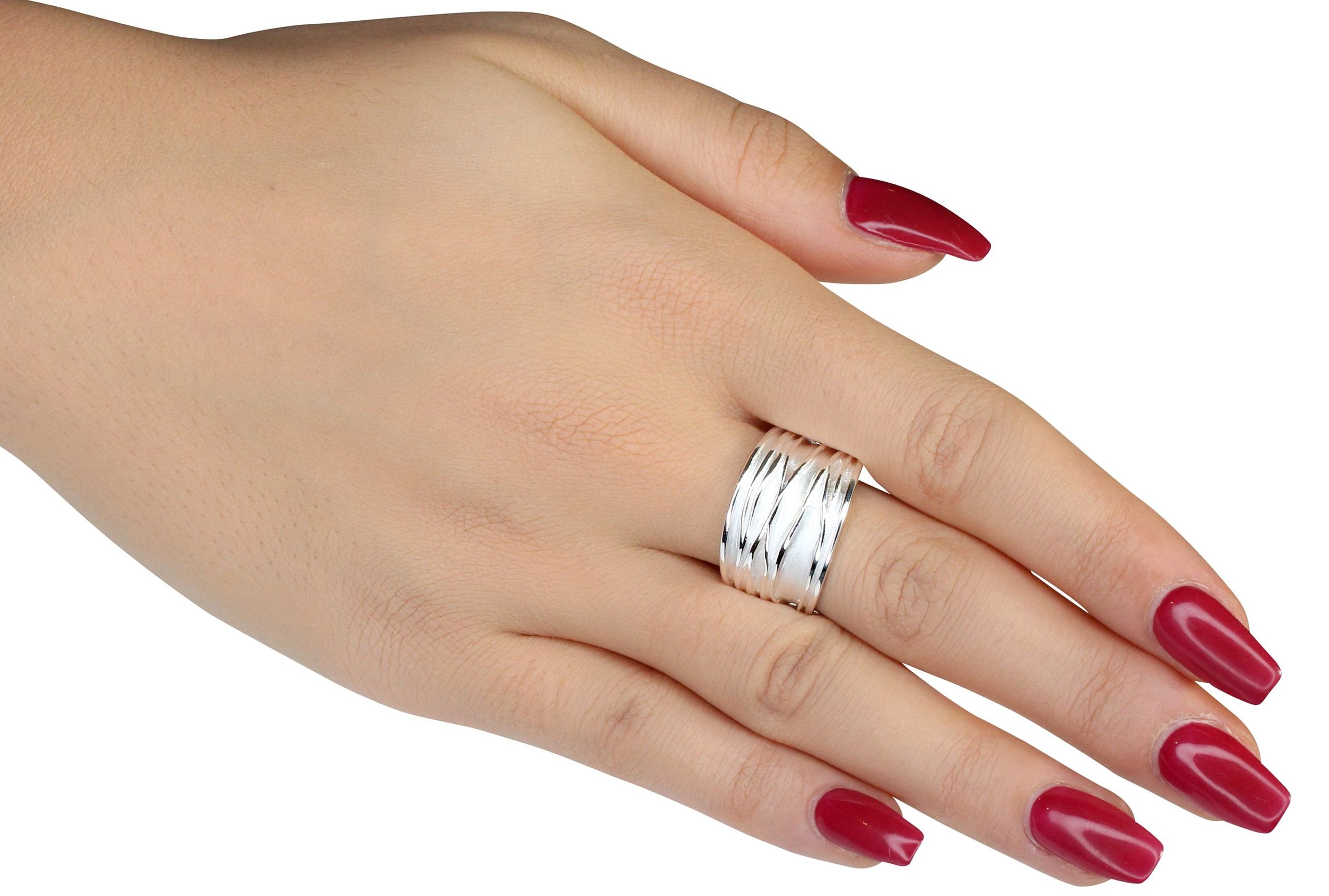 Ein Silberring für Damen mit einer gefalteten Wellenstruktur als Oberfläche getragen an einer Damenhand, wobei sich die Ringschiene nach unten hin verjüngt.