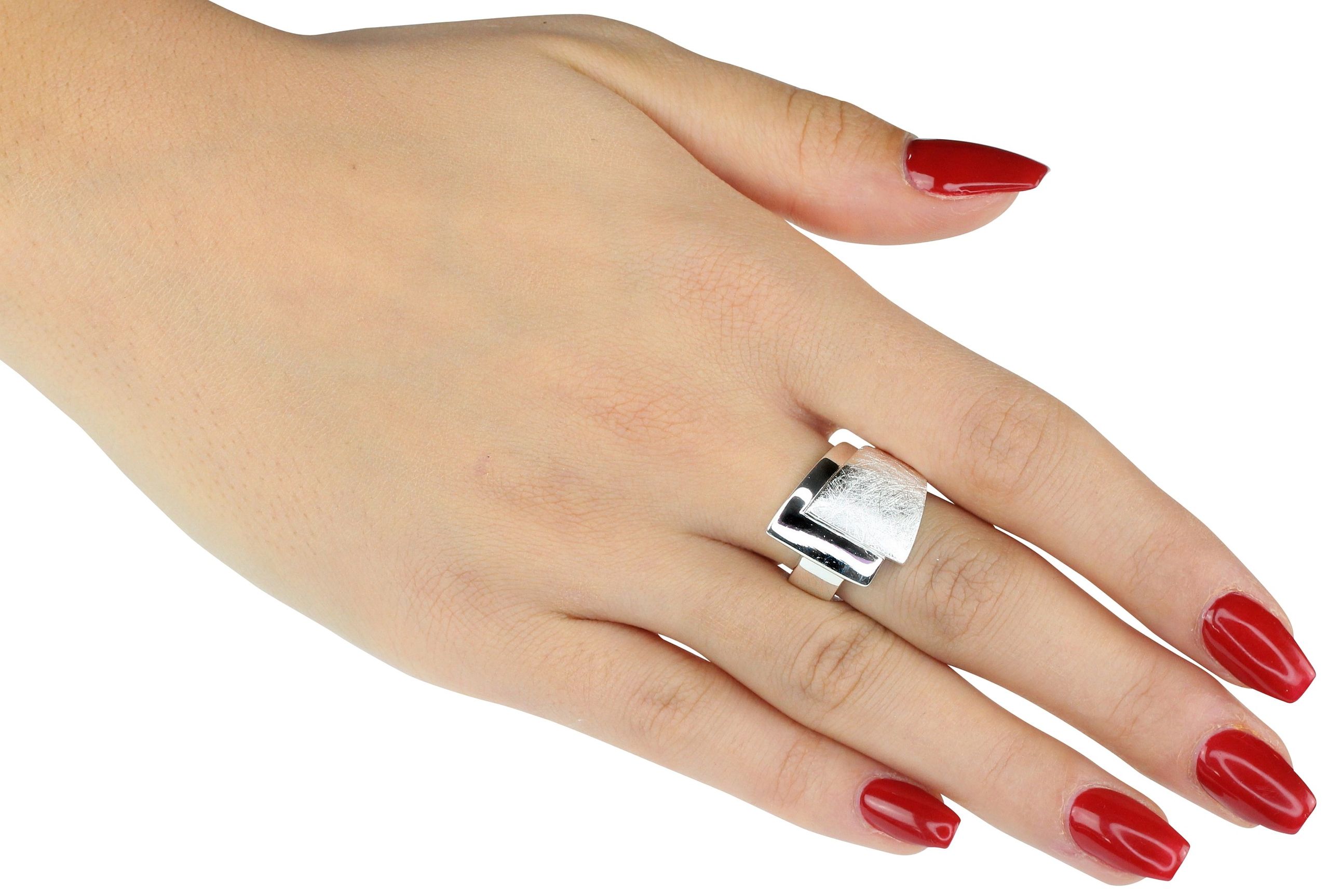 Ein Bandring aus Silber für Damen, bei dem ein oberer gebürsteter Ring mit einem unteren glänzenden Ring zu einem Schmuckstück verschmilzt, getragen an einer Damenhand.