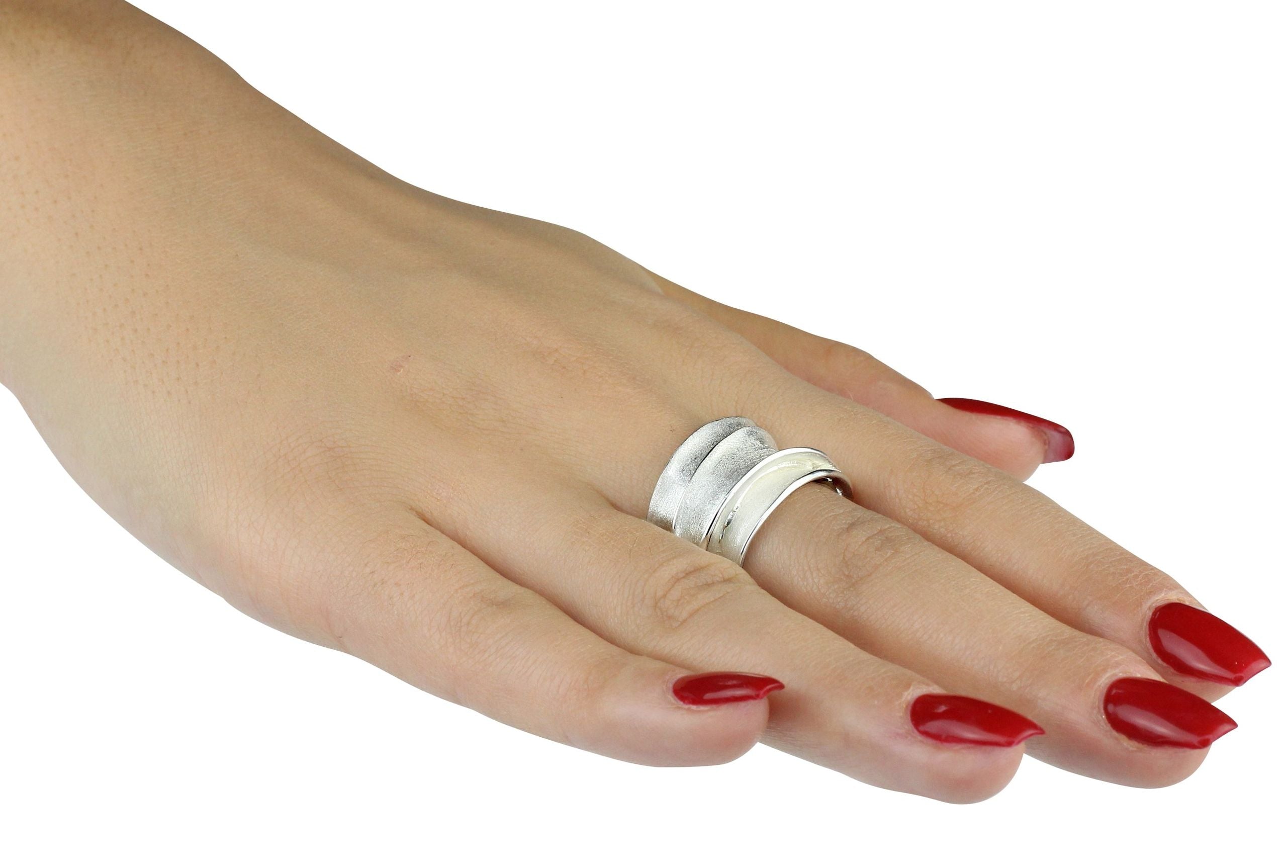 Ausdrucksstarker Wickelring aus Silber für Damen in markantem Design, getragen an einer Damenhand.
