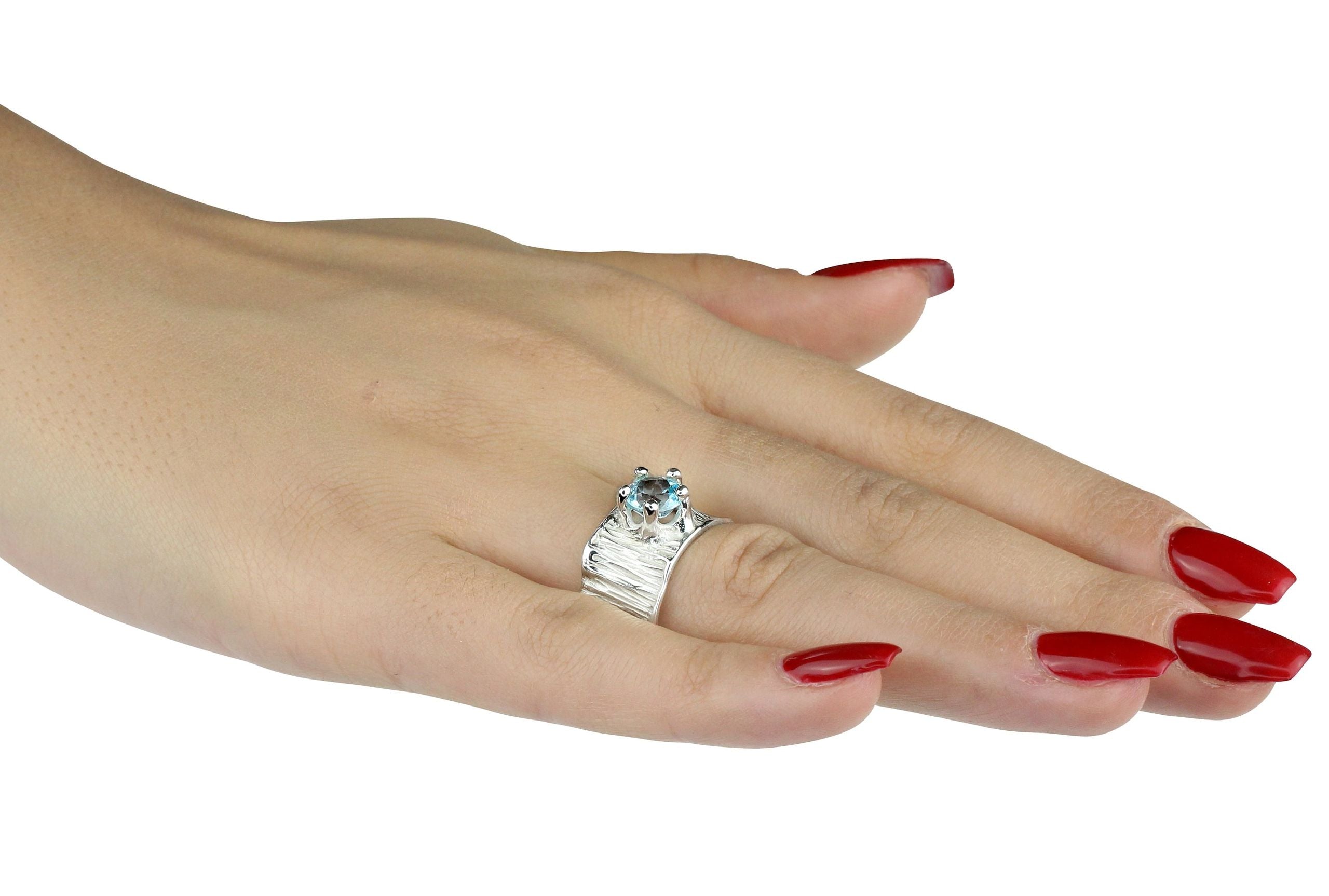Ein Silberring mit Blautopas getragen an einer Damenhand. Der klare Topas im Sternschliff ist in einer Krone mit fünf Zacken gefasst.