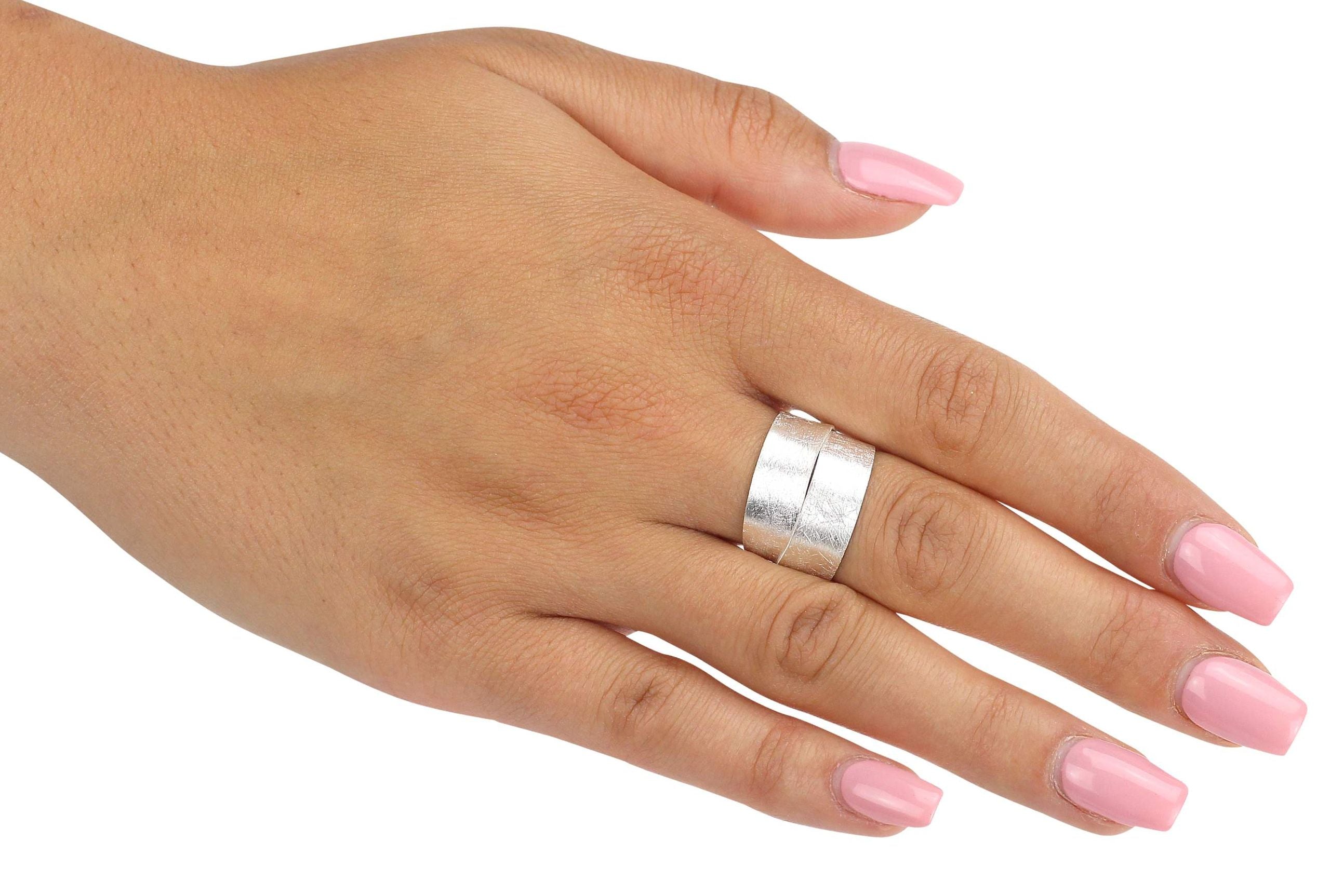 Ein geschmiedeter Ring aus Silber mit einer doppelt gewickelten Ringschiene, getragen an einer Damenhand.