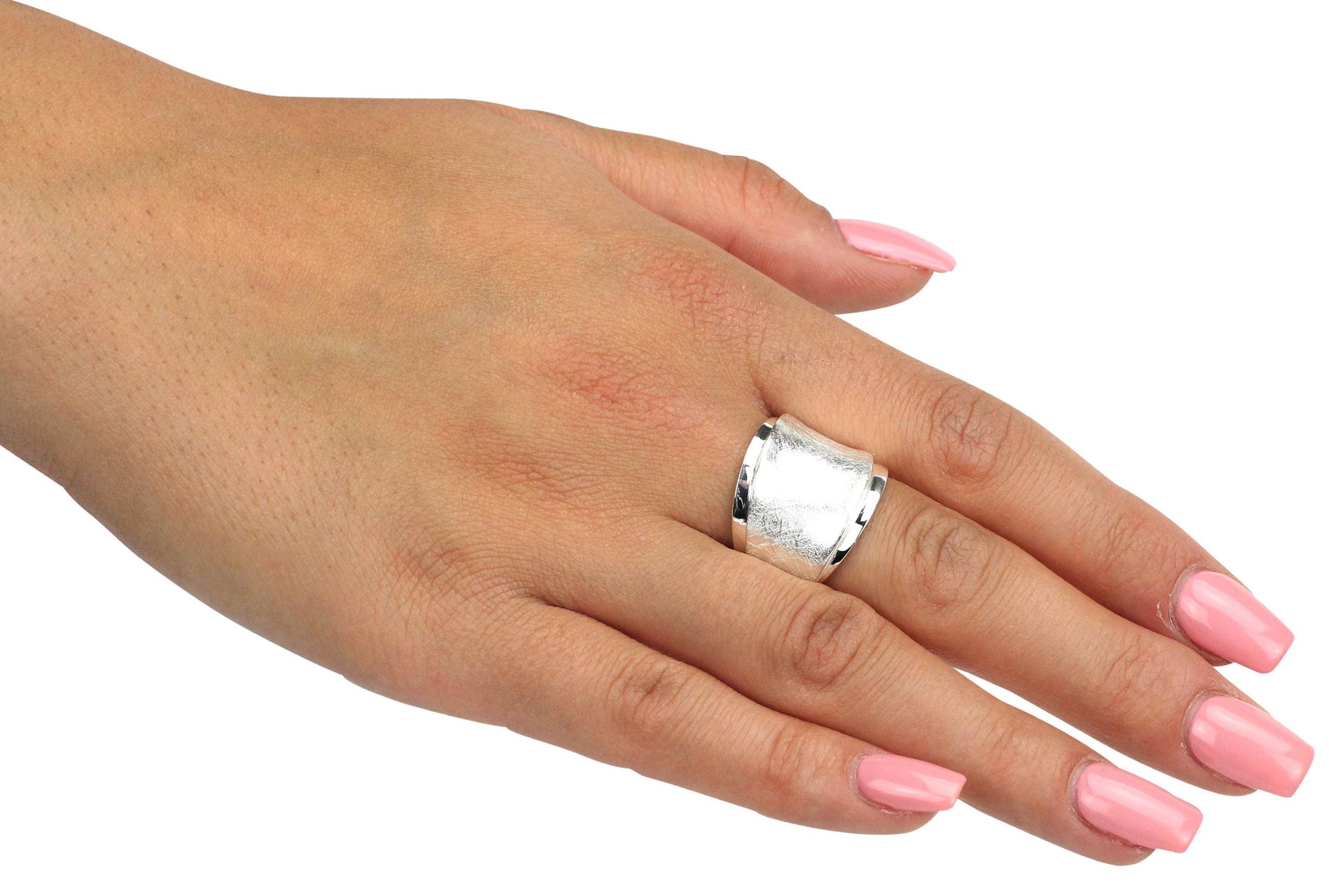 Ein Design Bandring aus Silber, bei dem ein mattierter und ein glänzender Ring gestuft übereinander liegen, getragen an einer Damenhand.