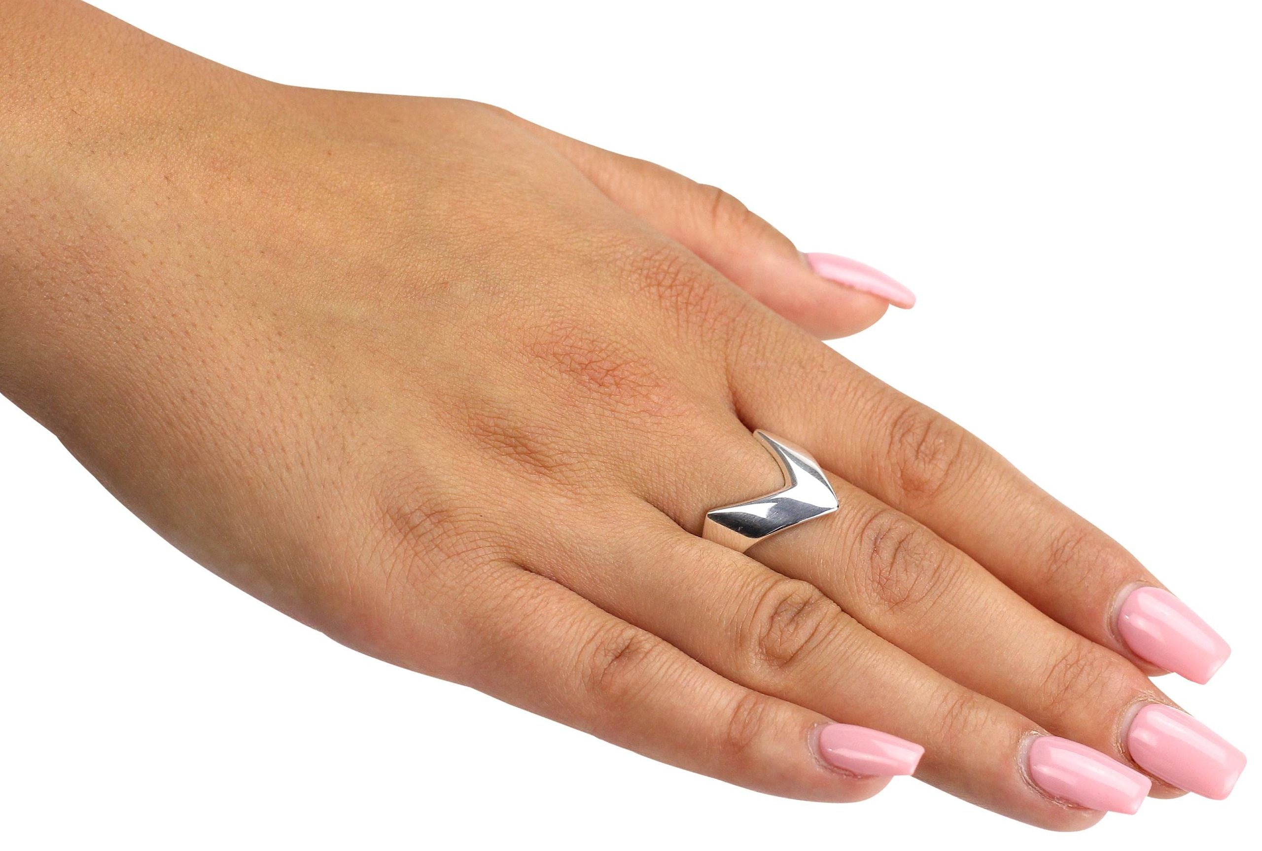 Ein spitz zulaufender Bandring aus Silber, der am Finger wie ein kleiner Pfeil nach vorne zeigt, getragen an einer Damenhand.