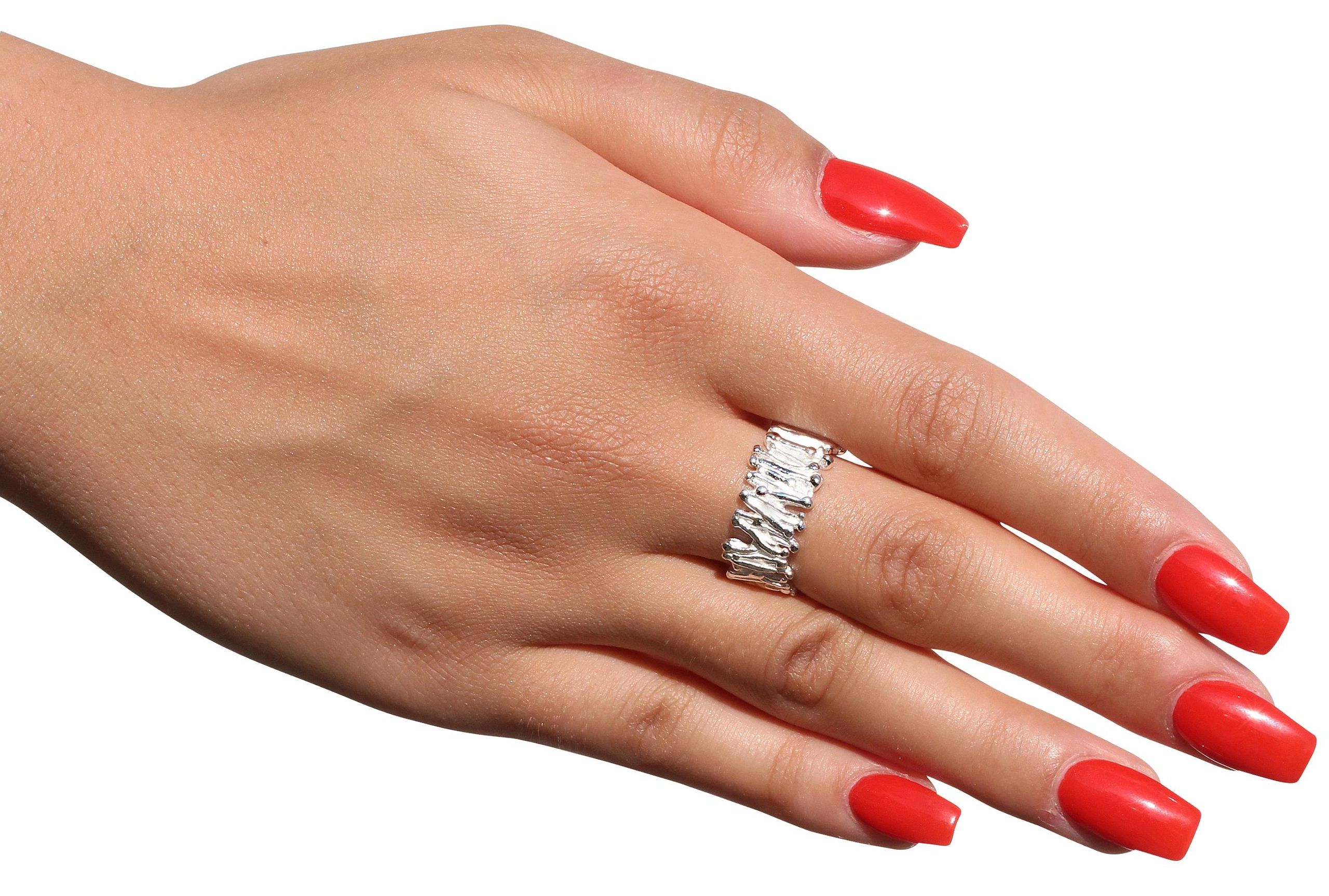 Ein Ring im Stäbchendesign für Damen und Herren aus Silber mit einer filigran gearbeiteten Oberfläche getragen an einer Damenhand.