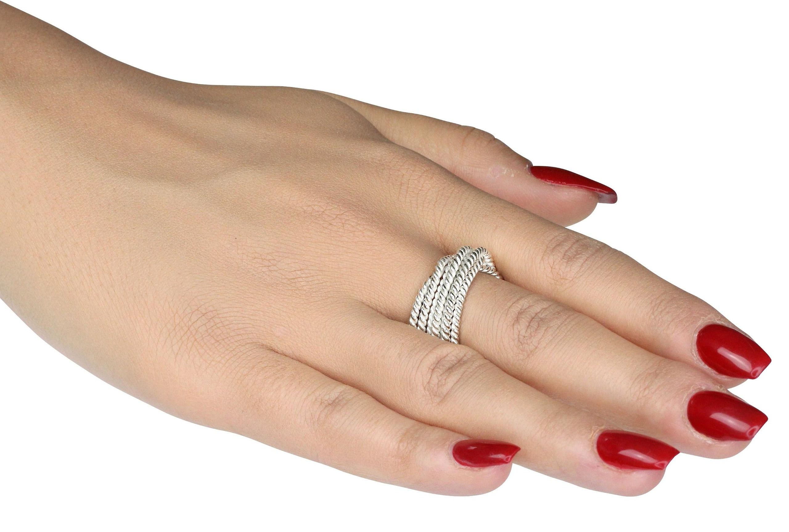 Attraktiver Wickelring für Damen aus Silber getragen an einer Damenhand. Der Ring ist gekordelt und hat eine teils matte, teil glänzende Oberfläche.