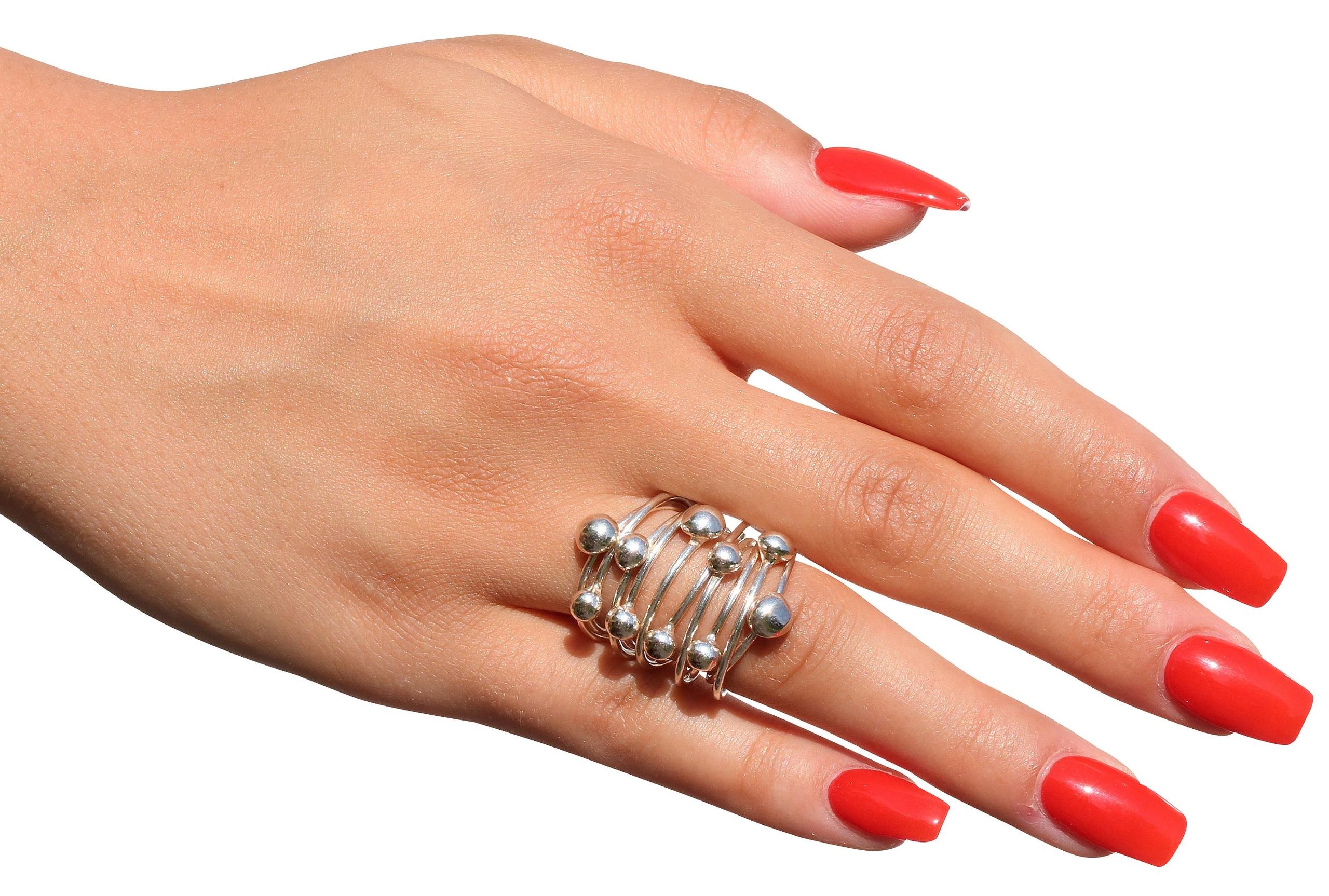 Kugelring aus Silber für Damen bestehend aus zehn beweglichen kleinen Ringen auf denen jeweils eine kleine Kugel thront, getragen an einer Damenhand.