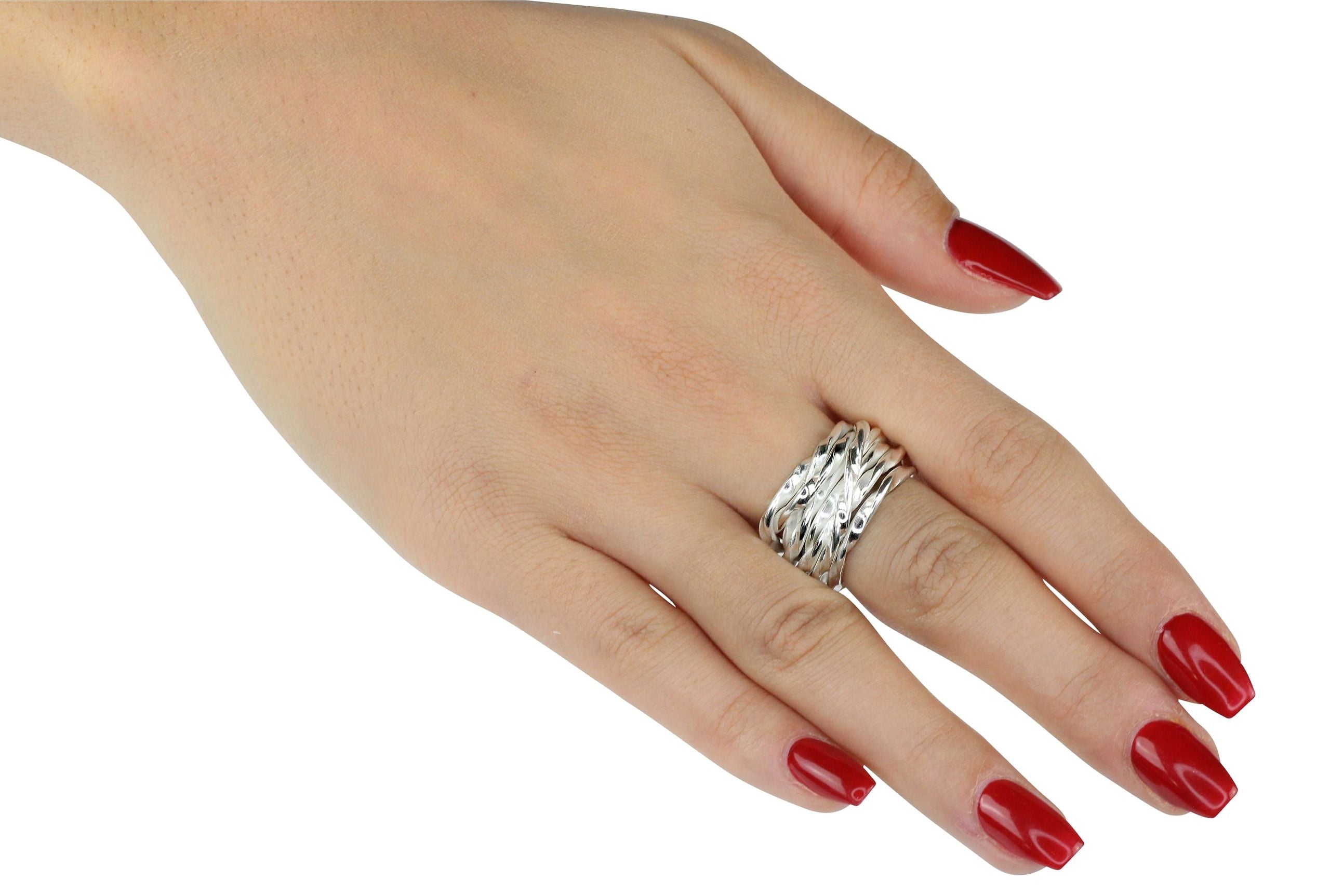 Ein Wickelring aus Silber für Damen, gearbeitet aus einem schlanken leicht gekordelten Strang, der sich mehrfach um den Finger wickelt, getragen an einer Damenhand.