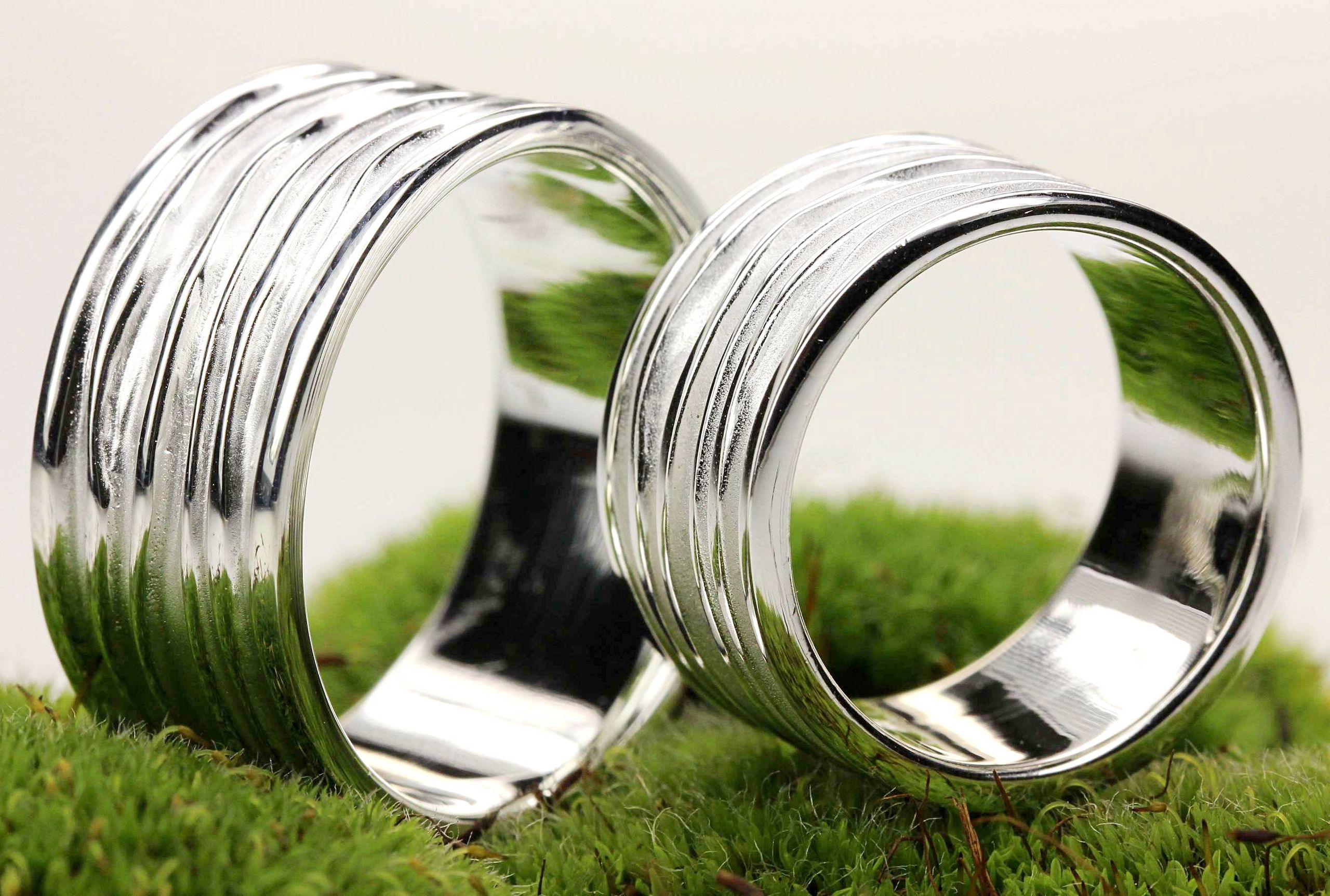 Zwei breite Silberringe mit einer gefalteten Wellenstruktur als Oberfläche. Der Ring bietet sich als Schmuck für Damen und für Herren an, daher ist er hier im Bild als Partnerring in Szene gestzt.