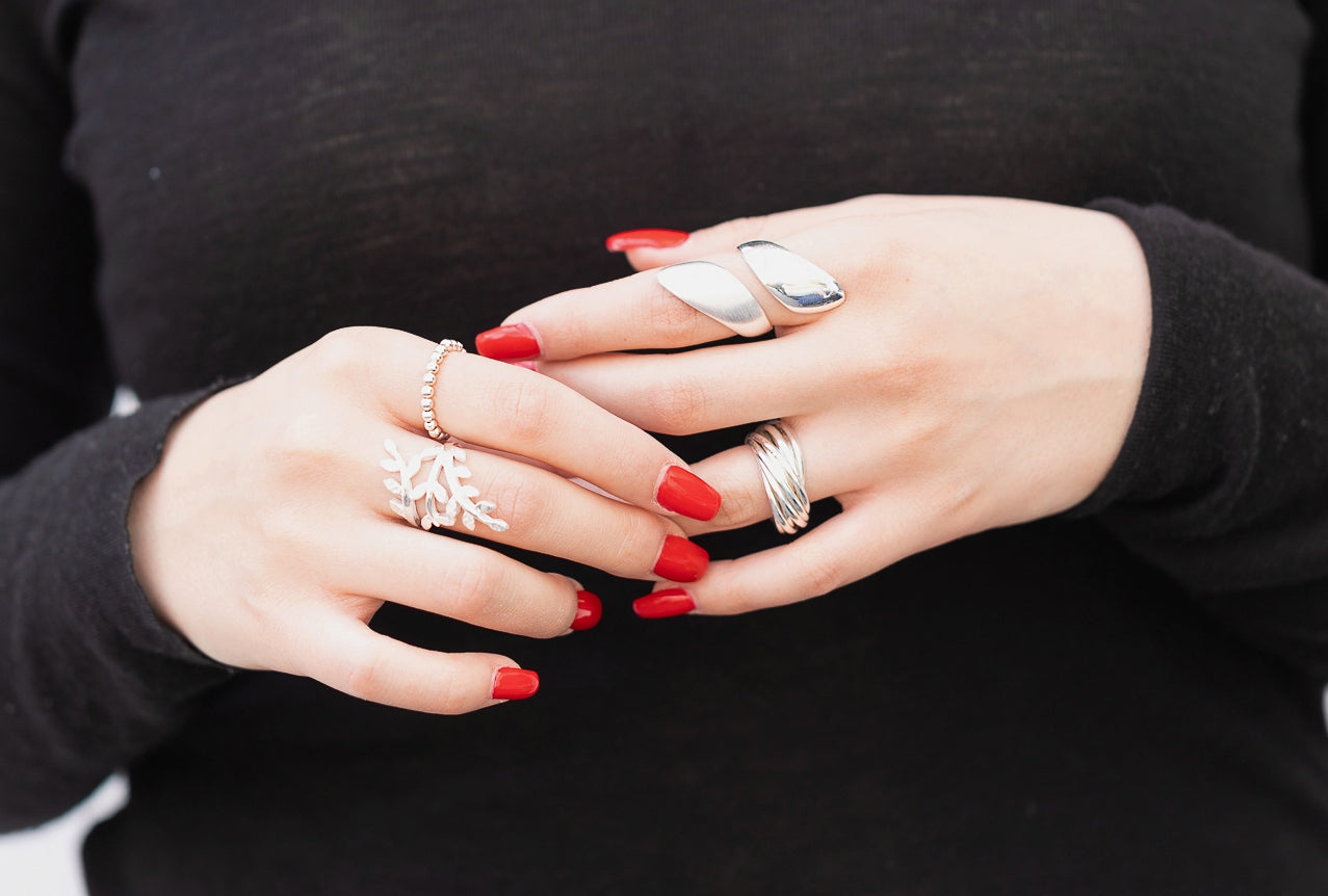 Mehrfachring aus Silber in den Größen 64 bis 70, bestehend aus zwölf einzelnen kleinen Ringen mit glänzender Oberfläche, getragen an einer Damenhand.