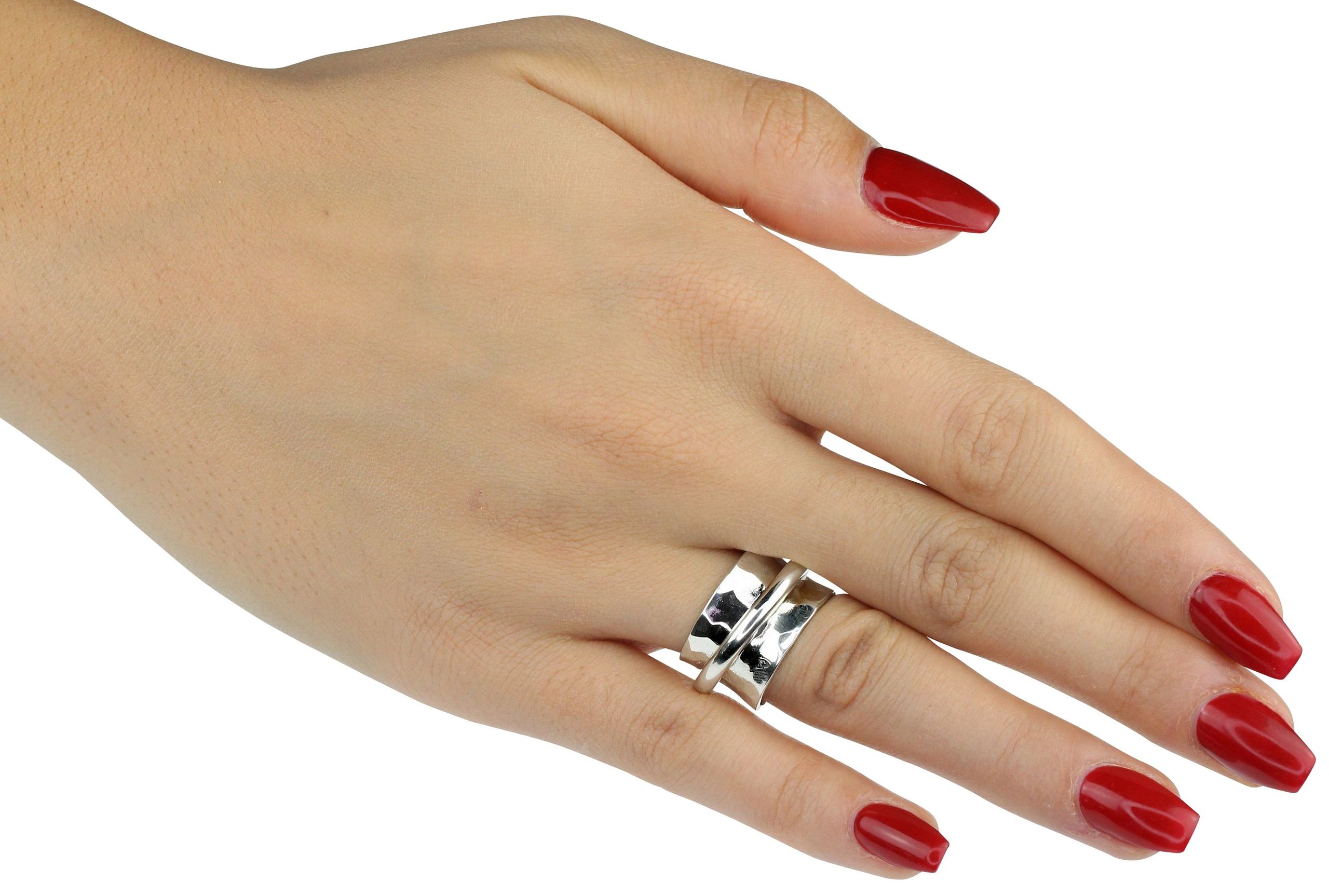 Ein moderner Schmiedering aus Silber getragen an einer Damenhand. Der Ring besteht aus einem massivem Bandring und einem kleinen Drehring, der unverlierbar darauf geschmiedet ist.